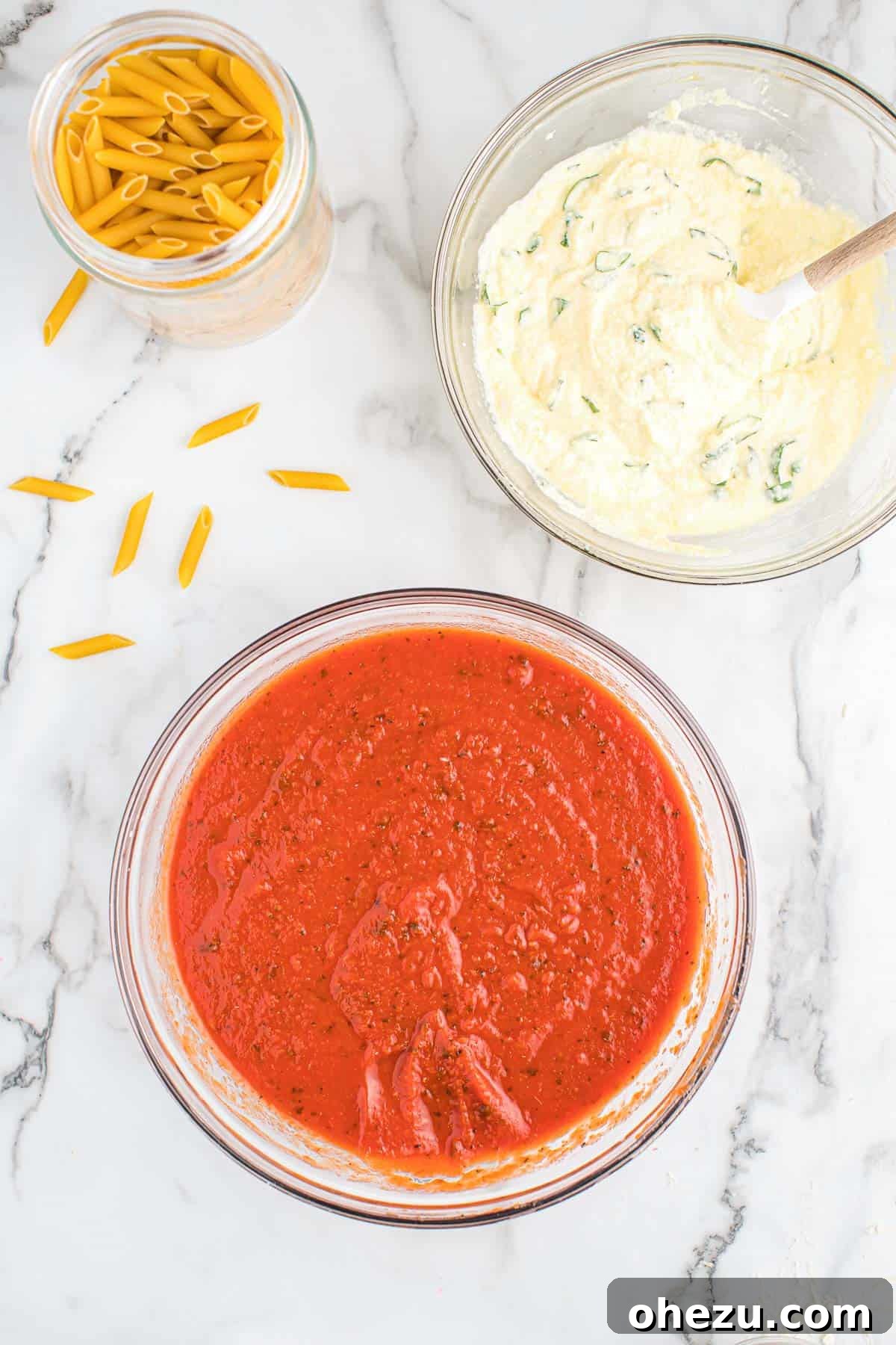 Effortless Slow Cooker Baked Ziti 6 Individual bowls containing uncooked penne pasta, the rich ricotta filling, and the combined pasta sauce, all prepped for layering.
