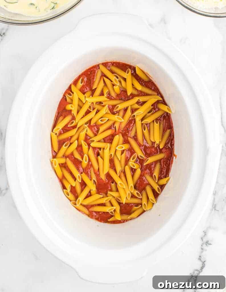 Effortless Slow Cooker Baked Ziti 8 The first layer of uncooked penne pasta carefully spread over the sauce in the slow cooker.