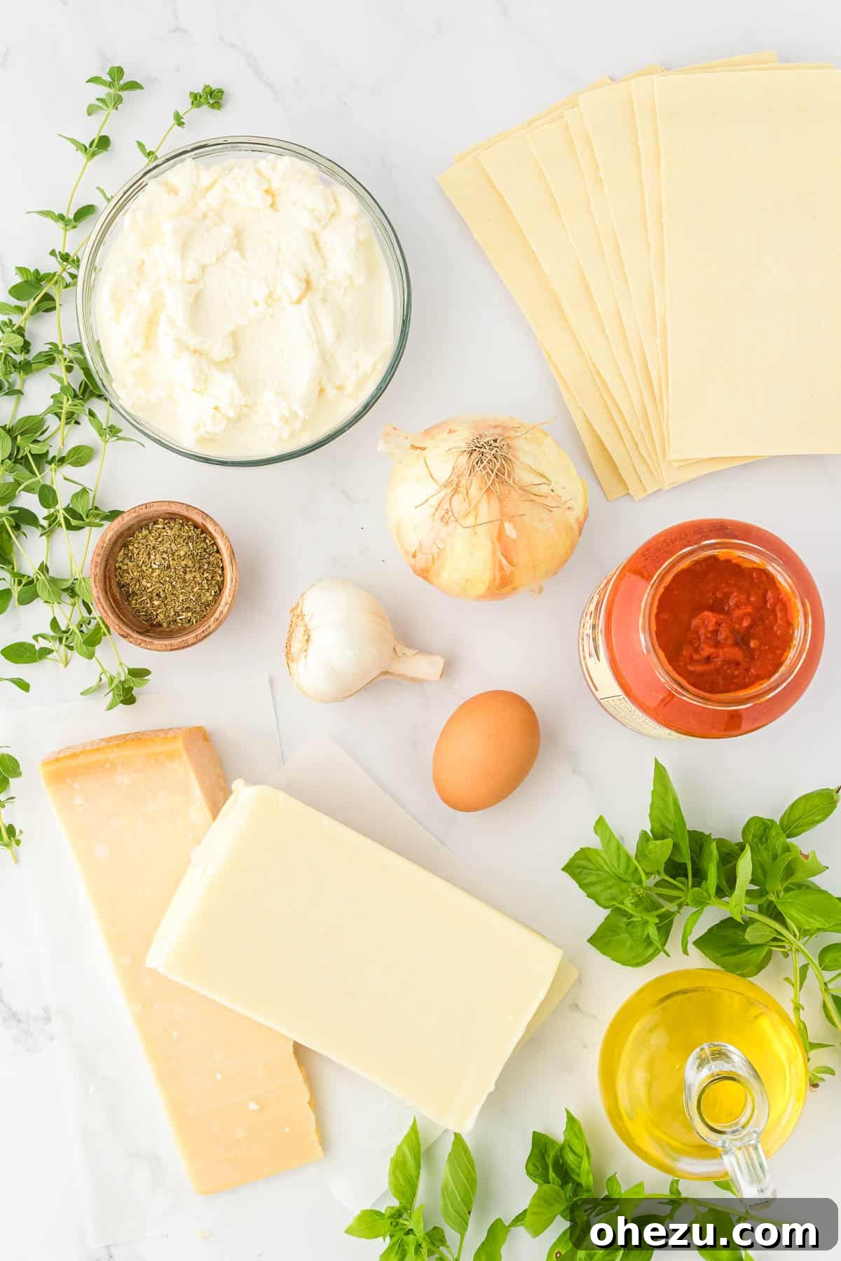 Triple Cheese Lasagna 3 A selection of fresh ingredients, including an onion, garlic cloves, various cheeses, and pasta sauce, neatly arranged for making lasagna.