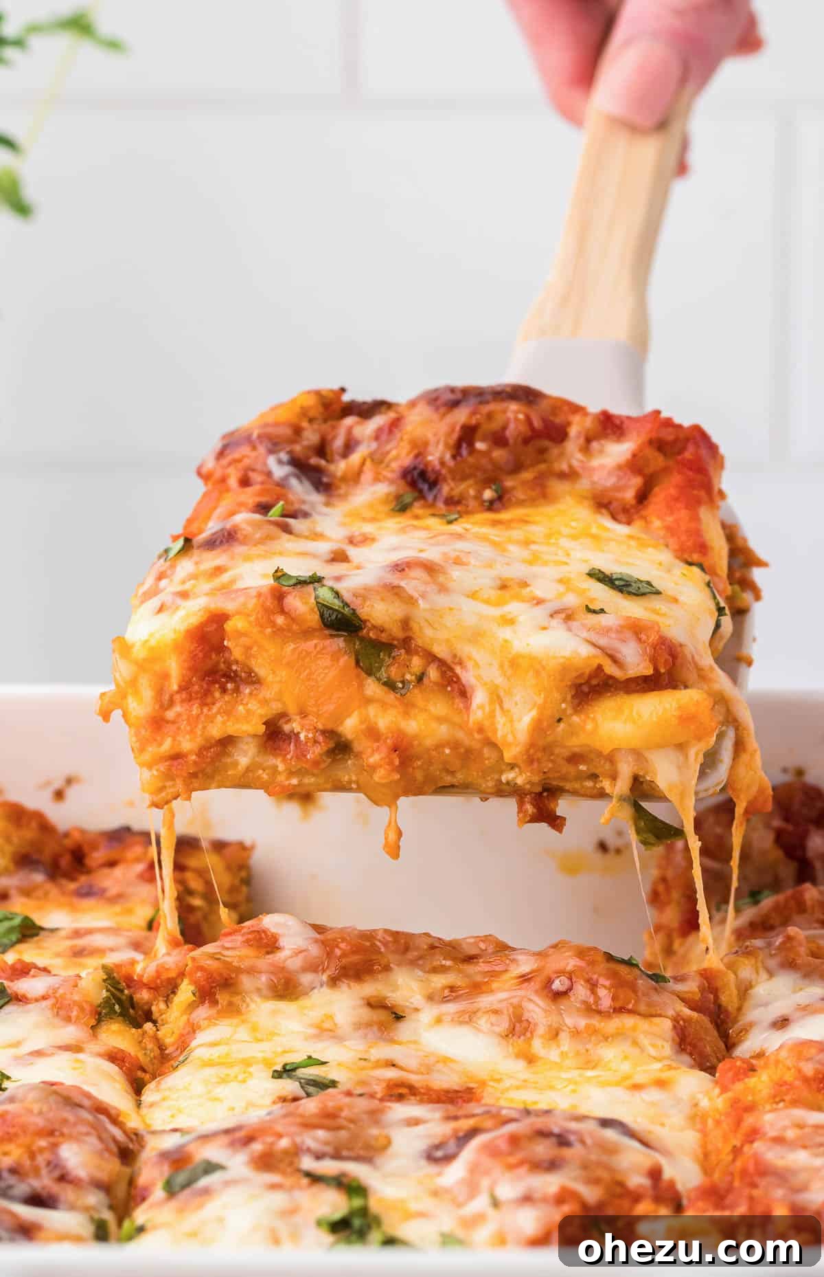 Triple Cheese Lasagna 29 A serving spatula lifting a perfect slice of homemade cheese lasagna from the baking dish, steam rising enticingly.
