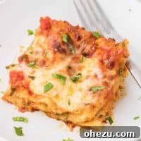 A delicious slice of cheese lasagna on a plate, garnished with fresh herbs, ready to eat.