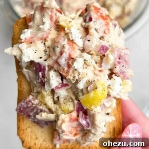 chicken salad piled on a cracker being held by hand.