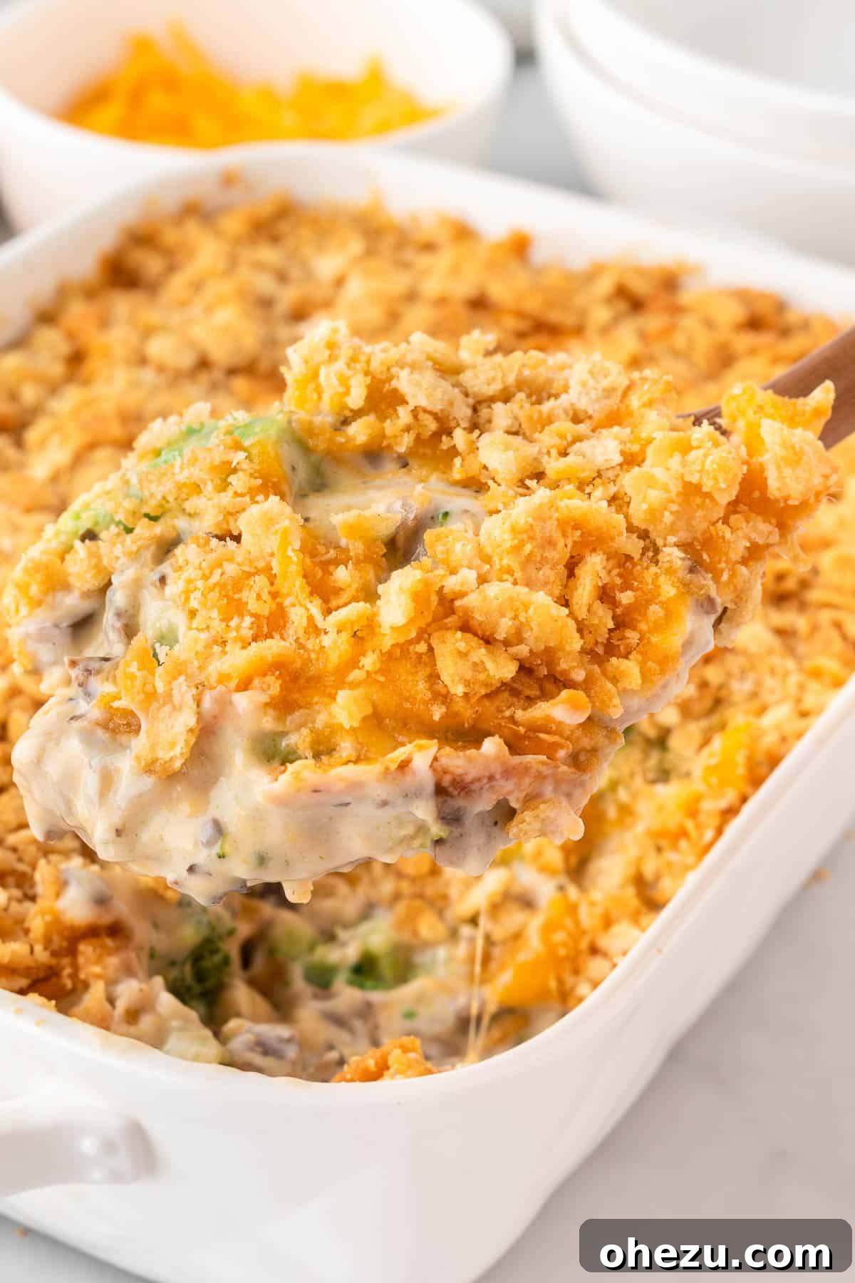 Another view of a wooden scoop taking a portion of Ritz broccoli casserole, showing steam
