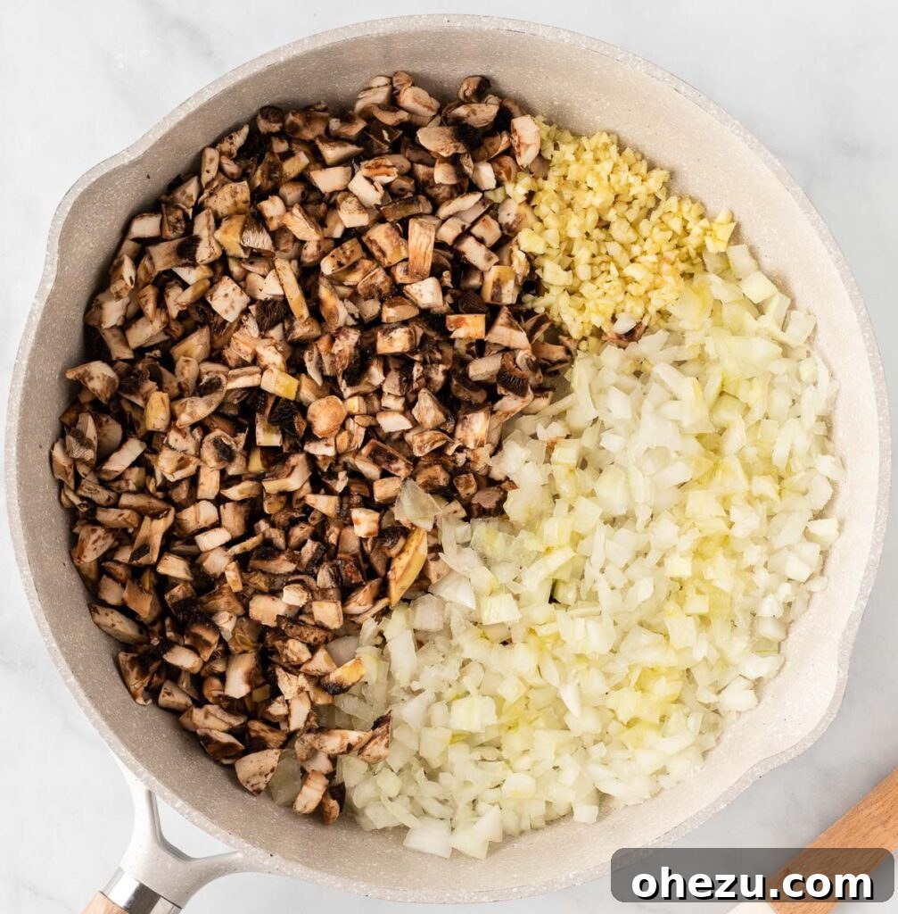 Mushrooms, garlic, and onion being sautéed in a skillet, turning golden