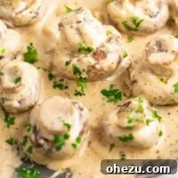 portobello mushrooms in cream sauce on a skillet sprinkled with fresh parsley
