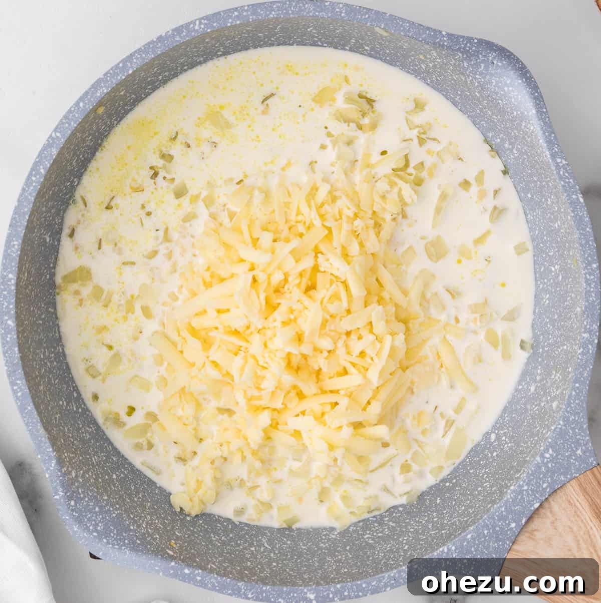 Ultimate Cheesy Brussels Sprouts 8 Shredded sharp white cheddar cheese being stirred into the simmering heavy cream and aromatics in a skillet, creating a rich sauce.