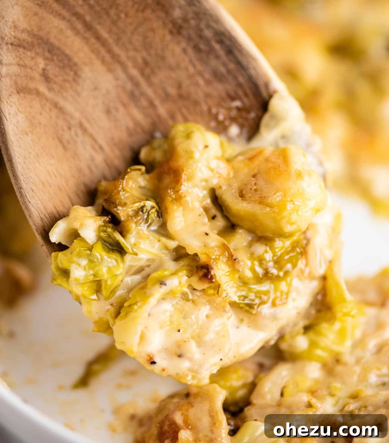 Ultimate Cheesy Brussels Sprouts 10 A wooden spoon scooping a generous portion of cheesy Brussels sprouts gratin, showing the creamy texture and melted cheese.