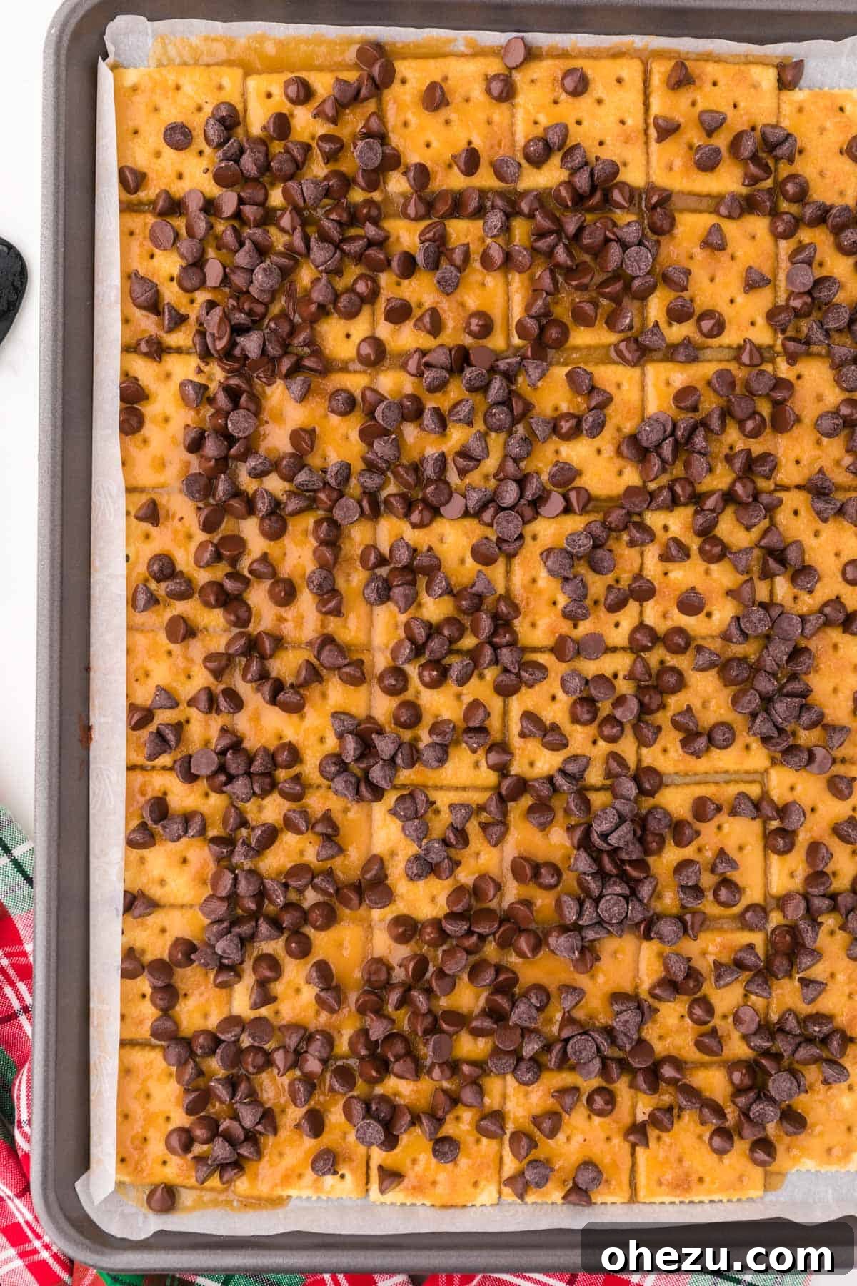 Irresistible Christmas Toffee Bark 11 Semi-sweet chocolate chips sprinkled generously over the hot toffee-covered saltines, beginning to melt.