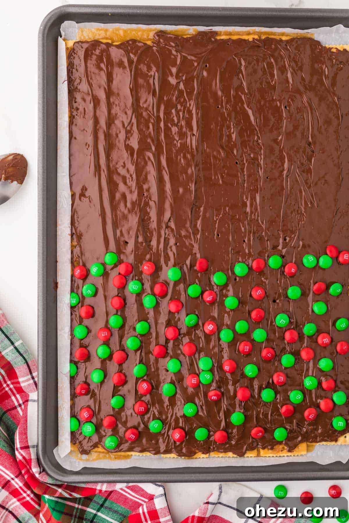 Irresistible Christmas Toffee Bark 12 Melted chocolate smoothly spread over the crackers, with half of the surface topped with vibrant red and green M&M's for a festive touch.