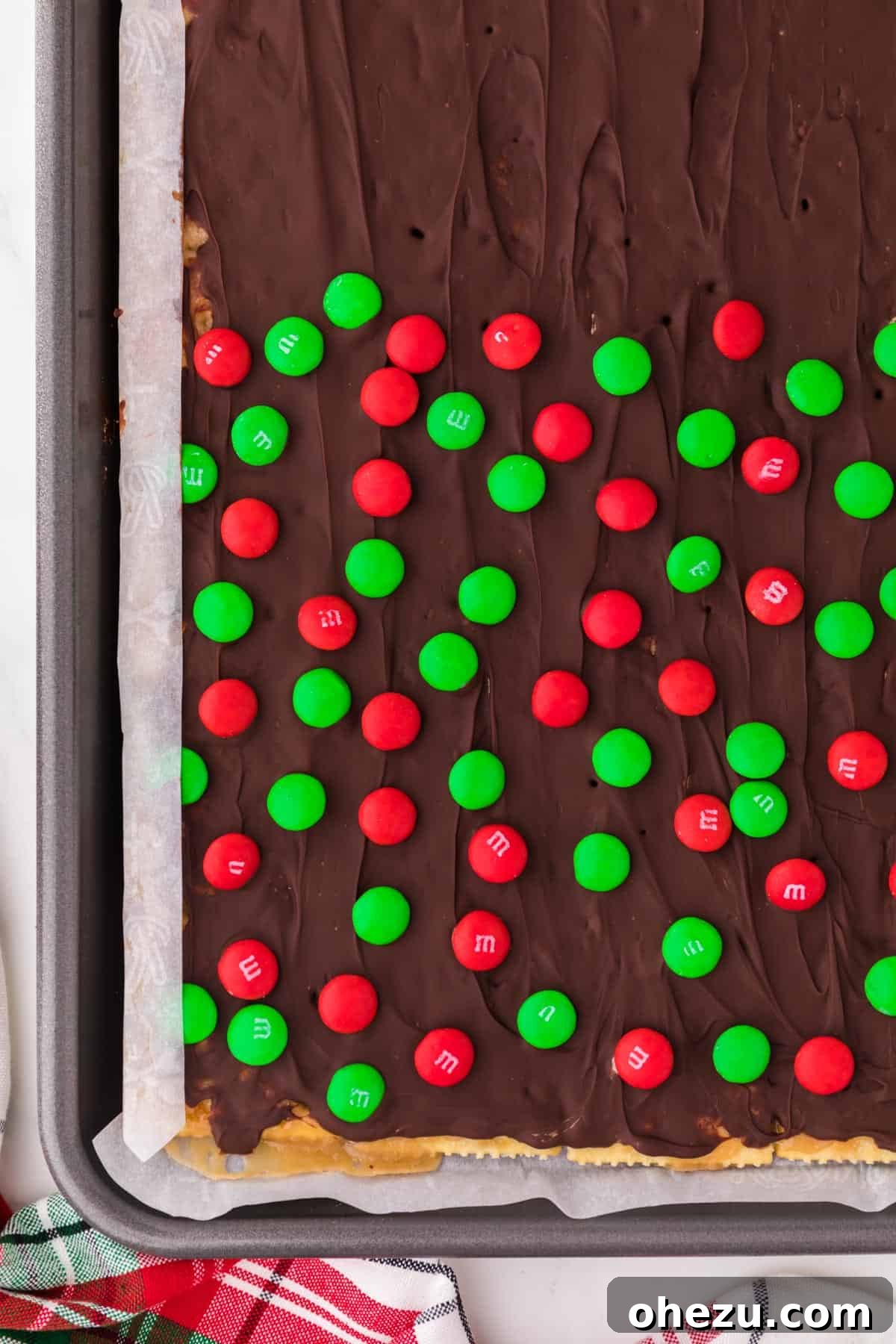 Irresistible Christmas Toffee Bark 13 Christmas Crack cooling on the baking sheet, with a layer of smooth melted chocolate and some festive toppings.