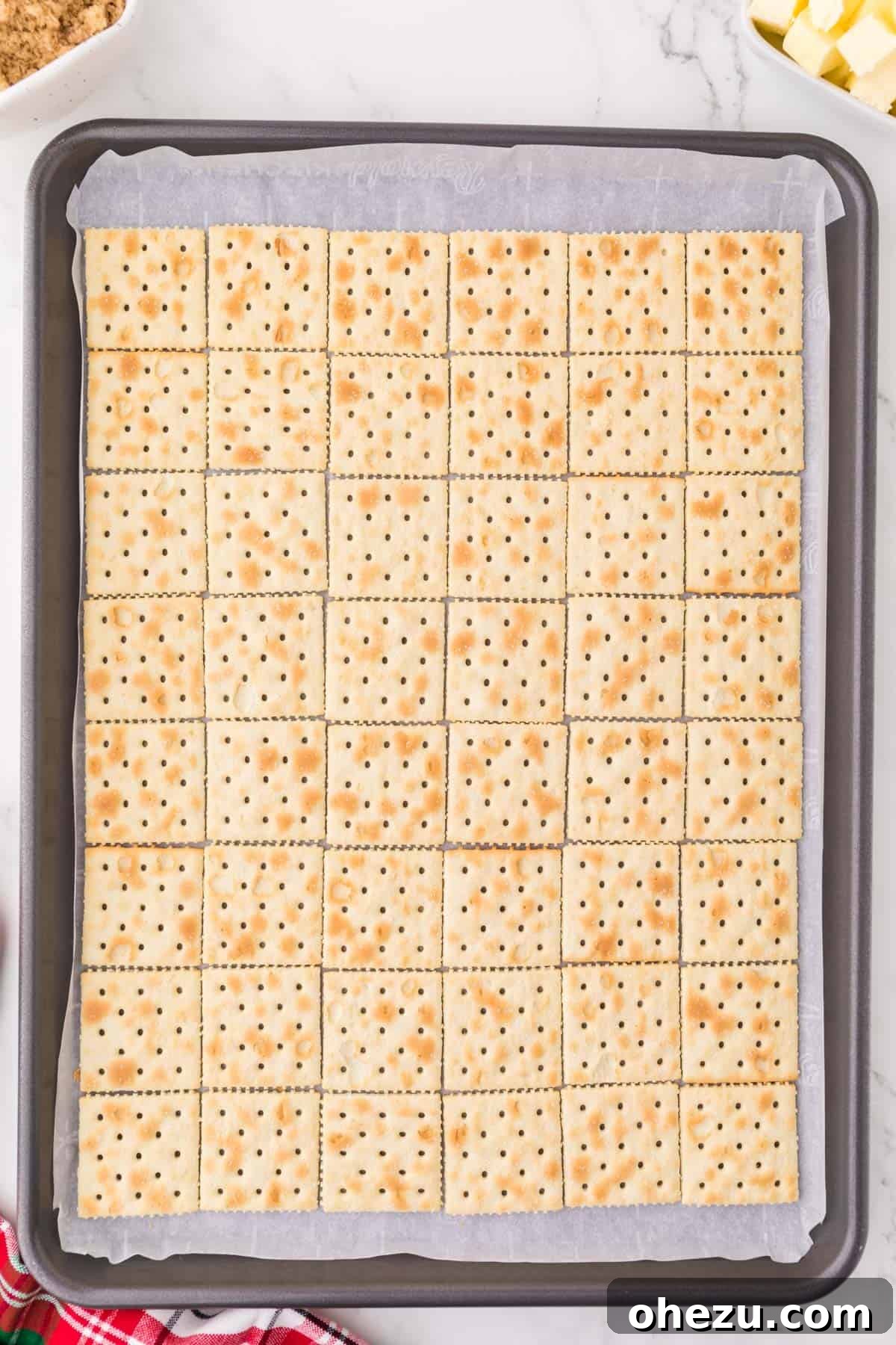 Irresistible Christmas Toffee Bark 6 Saltine crackers carefully lined up in neat rows on a baking sheet covered with parchment paper.