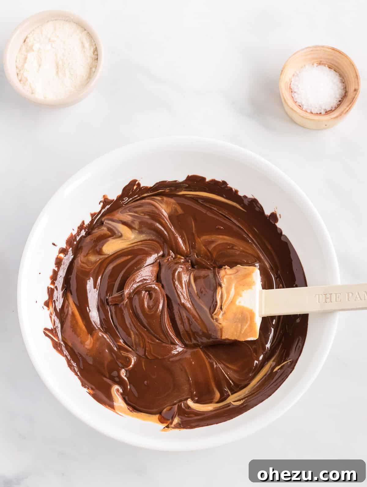 Decadent Vegan Peanut Butter Chocolate Fudge 4 Close-up view of rich, melted chocolate being smoothly mixed with creamy peanut butter in a glass bowl.