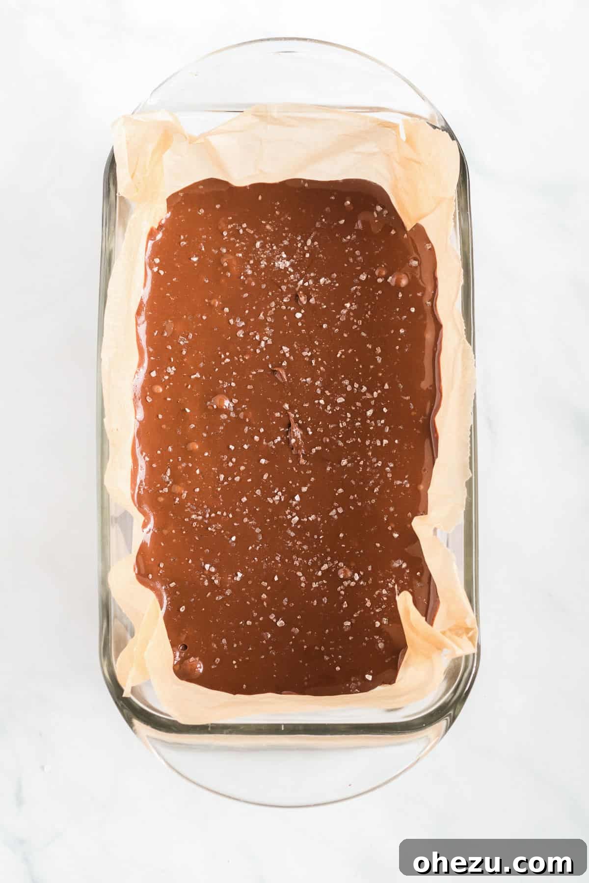 Decadent Vegan Peanut Butter Chocolate Fudge 6 The smooth vegan chocolate peanut butter fudge mixture being poured into a loaf pan perfectly lined with wax paper.
