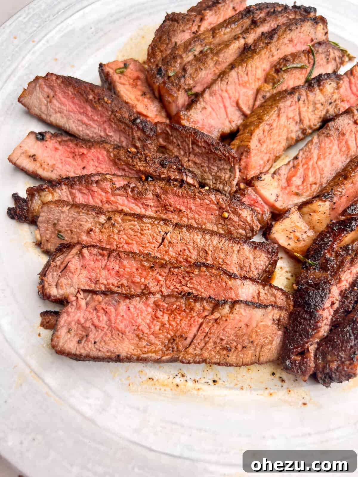 Rustic Herb Butter Steak 3 Slices of tender, perfectly cooked steak beautifully arranged on a white plate