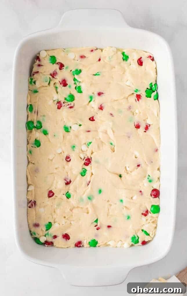 cookie bar batter spread in a white 9 by 13 baking dish