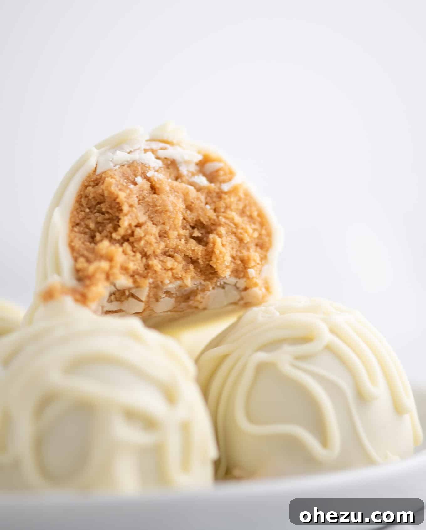 No-Bake White Chocolate Peanut Butter Delights 6 white chocolate truffles with a bite taken out to show the peanut butter filling