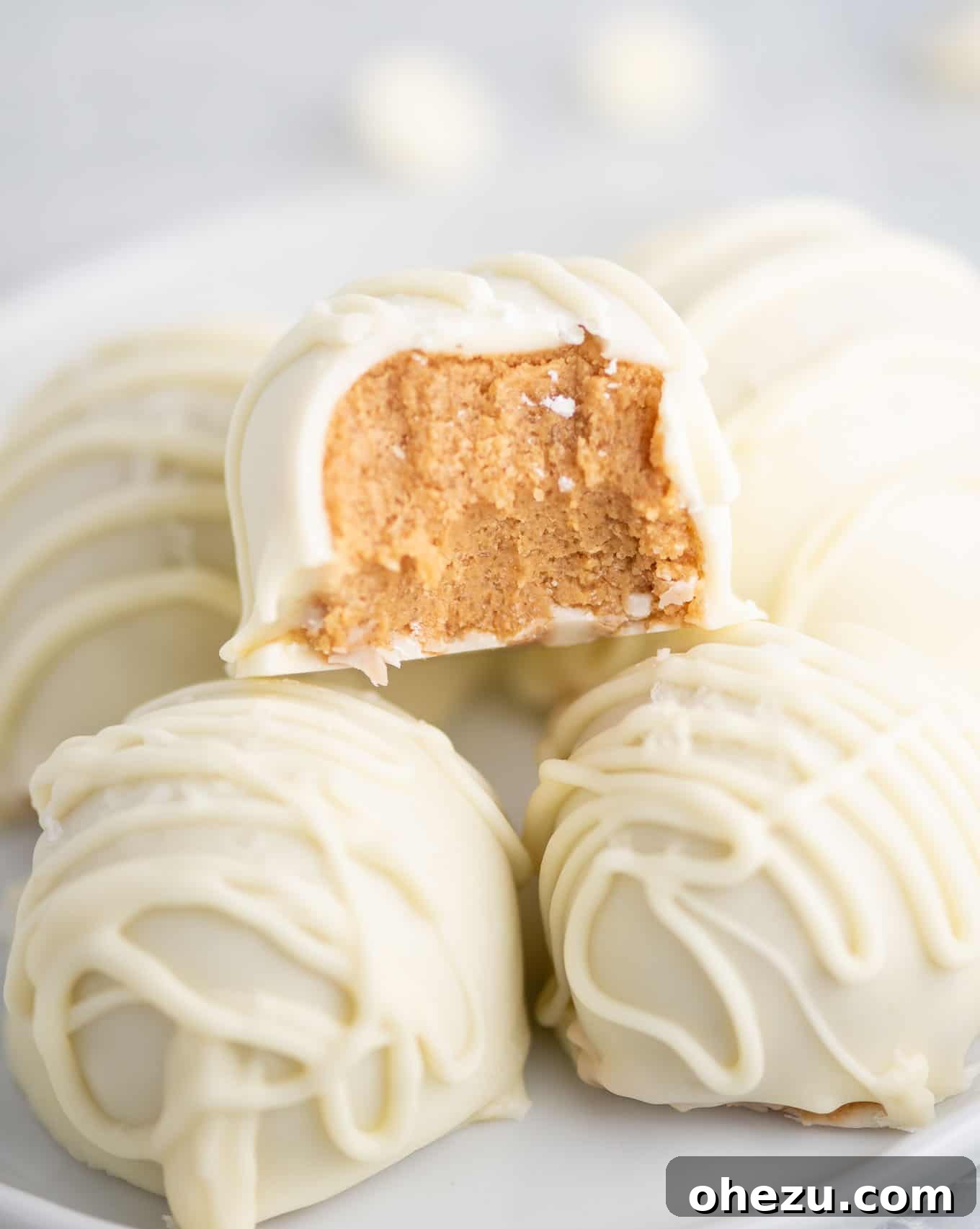 No-Bake White Chocolate Peanut Butter Delights 10 peanut butter balls stacked with one taken a bite out of