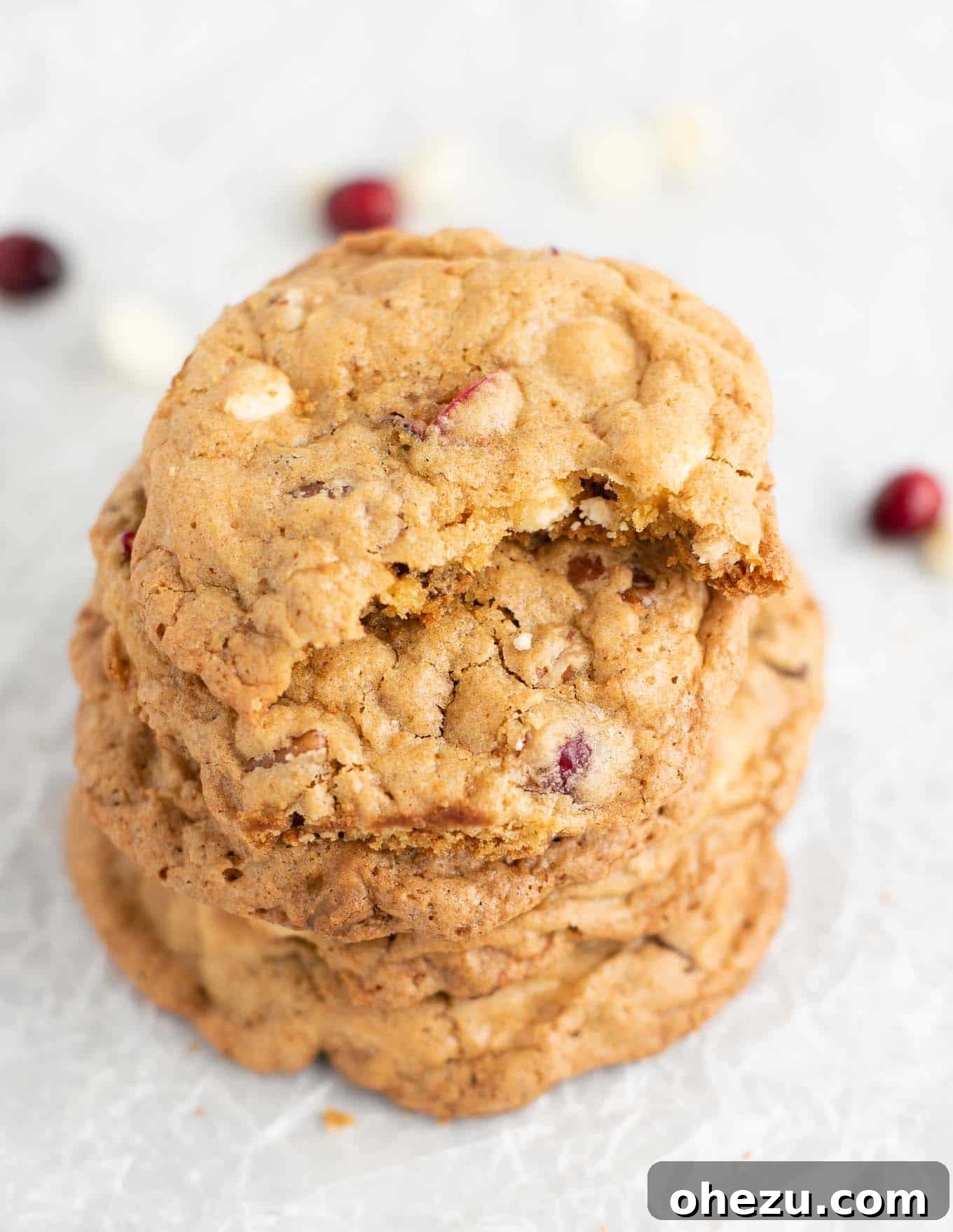 Decadent White Chocolate Cranberry Pecan Cookies 3 Close-up of a stack of fresh cranberry pecan cookies with a bite taken out, highlighting the delicious filling