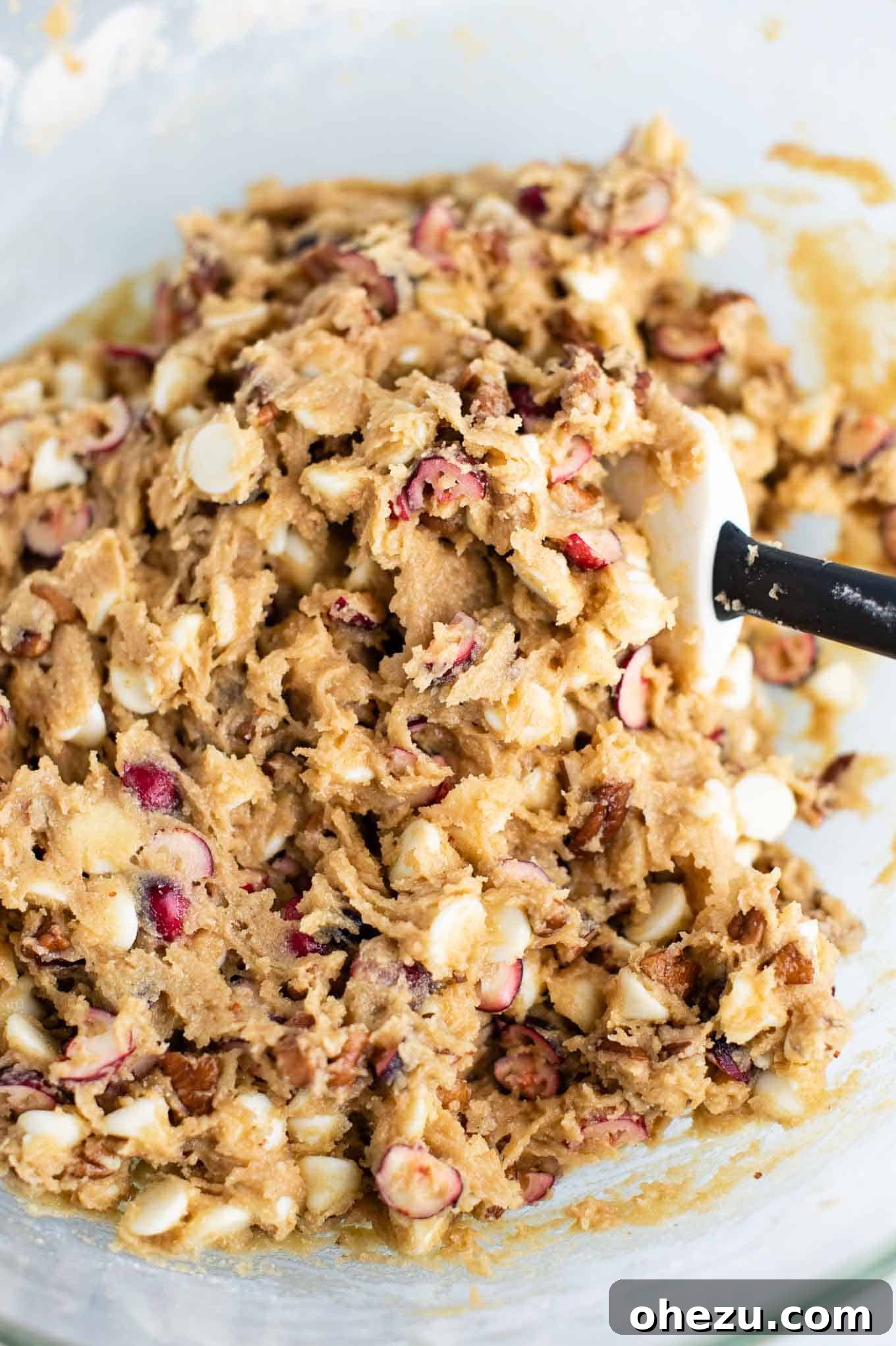 Decadent White Chocolate Cranberry Pecan Cookies 6 Cranberry pecan cookie batter mixed in a bowl with a rubber spatula, showing the rich texture and colorful mix-ins