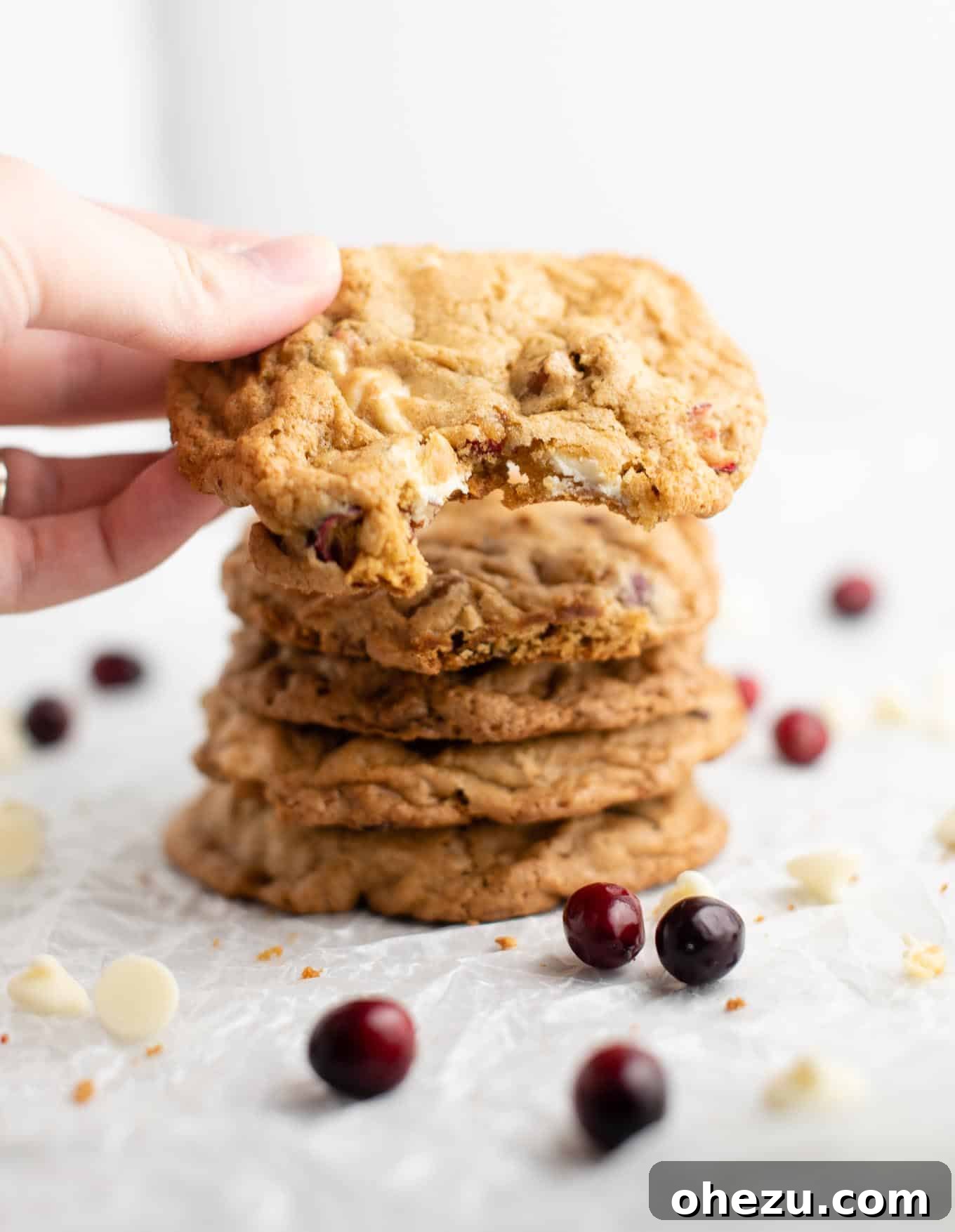 Decadent White Chocolate Cranberry Pecan Cookies 7 Hand holding a freshly baked white chocolate cranberry pecan cookie with a bite taken out, perfect for sharing