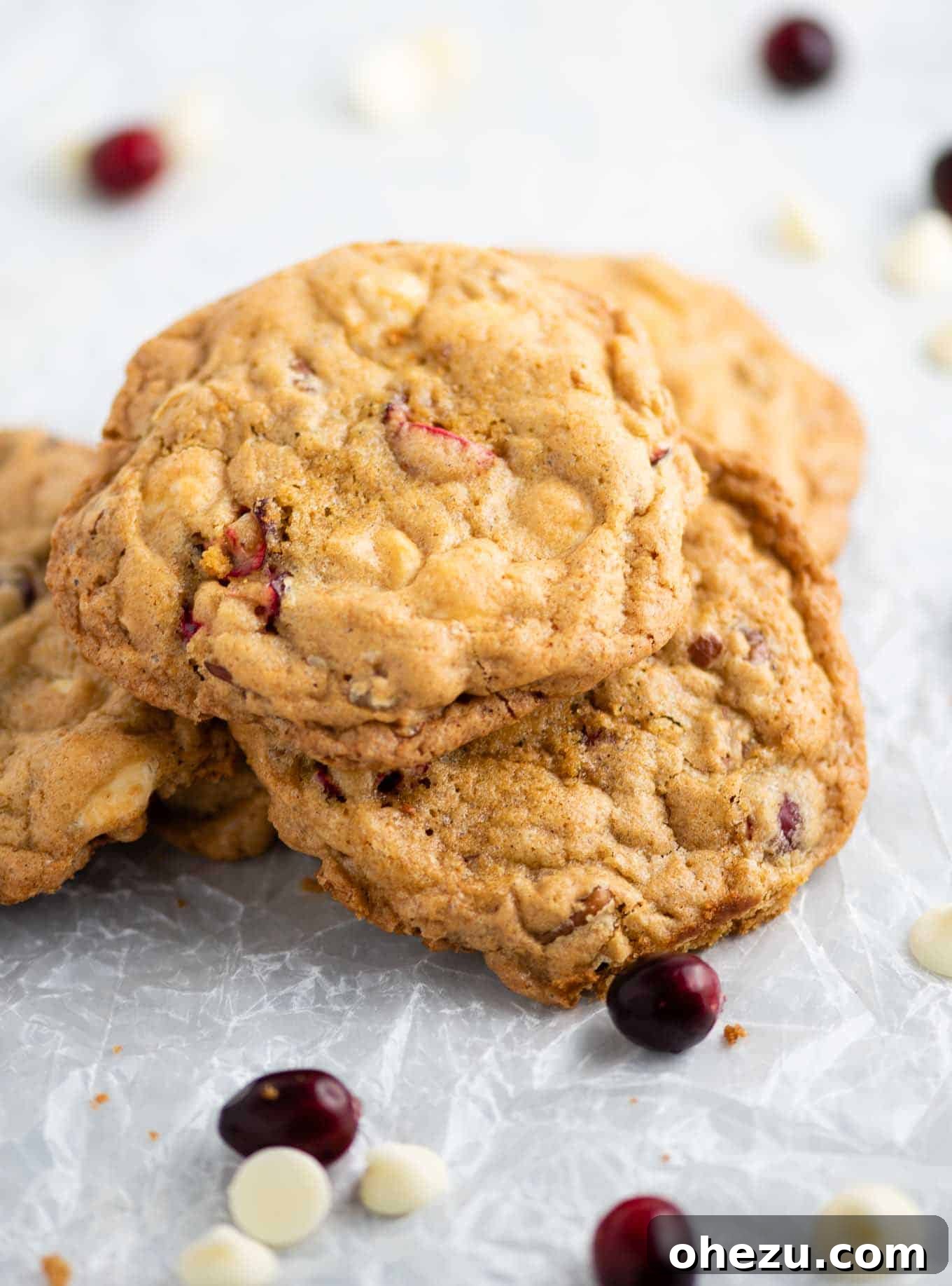 Decadent White Chocolate Cranberry Pecan Cookies 9 Artistic arrangement of baked cookies on crumbled wax paper with loose cranberries and white chocolate chips in the background