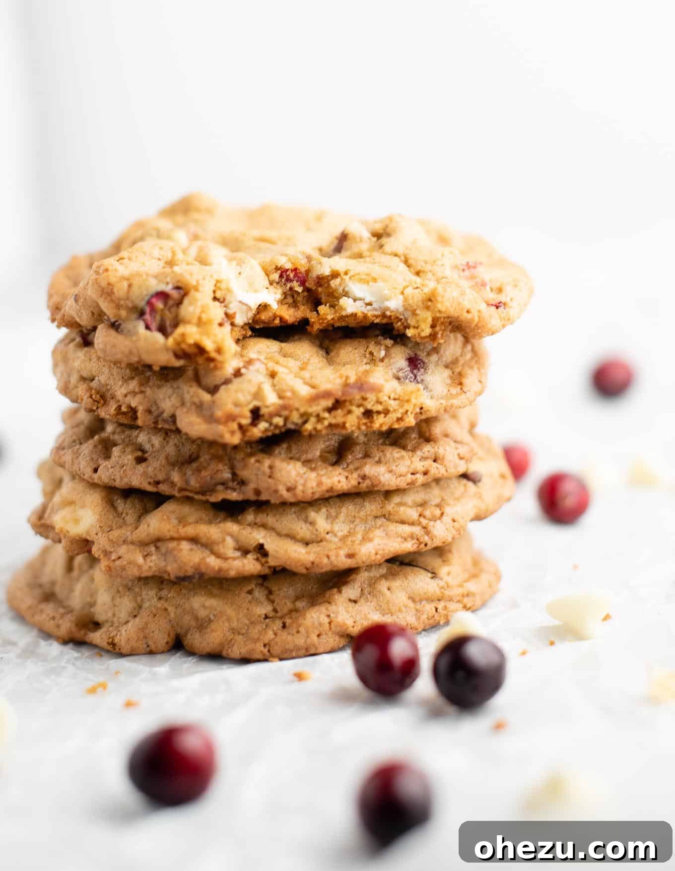 Decadent White Chocolate Cranberry Pecan Cookies 10 Stacked cranberry pecan cookies, one with a bite taken out, perfect for holiday dessert tables