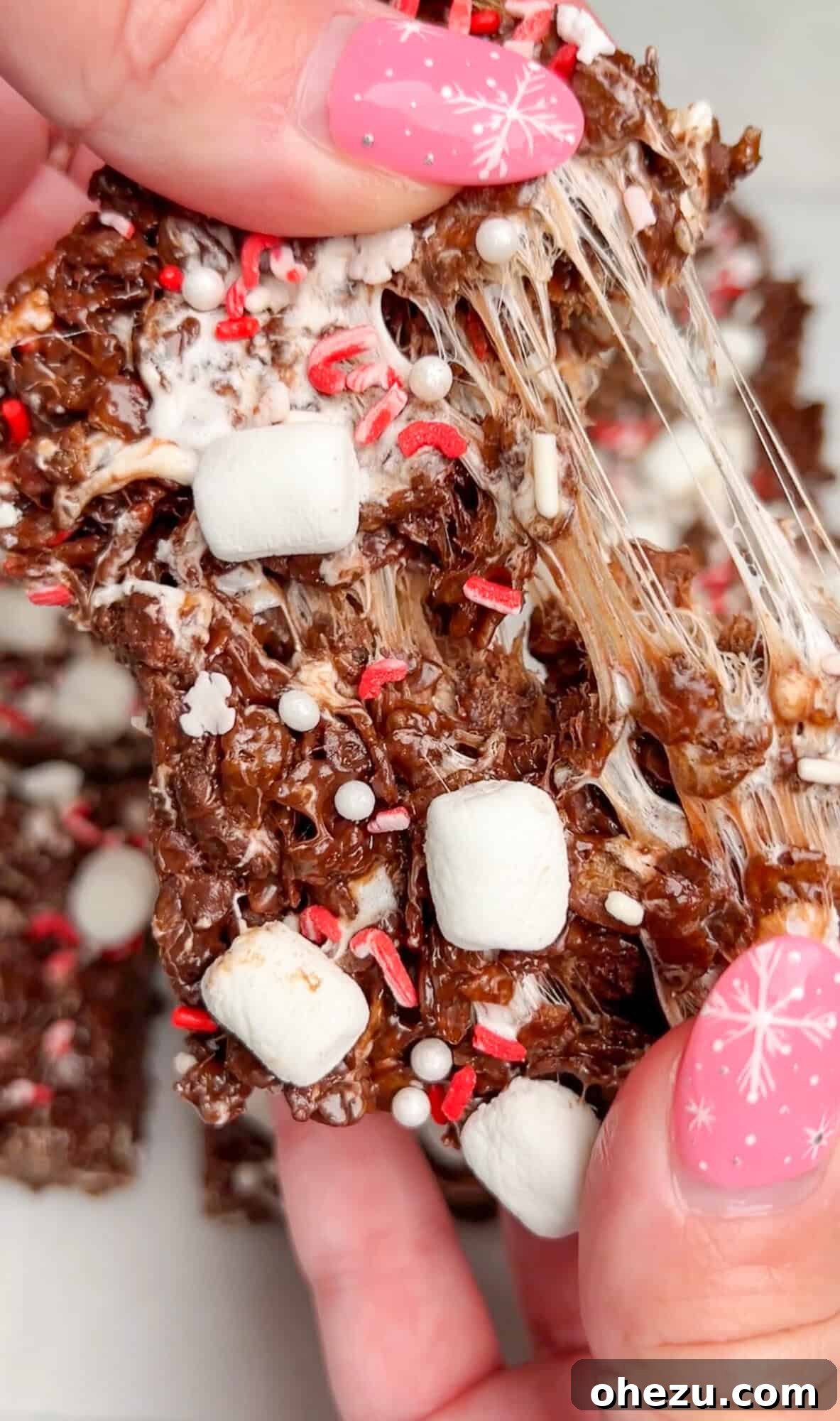Cozy Cocoa Crisps 14 A Hot Cocoa Rice Krispie Treat being pulled apart, showcasing its incredible gooey and chewy texture.