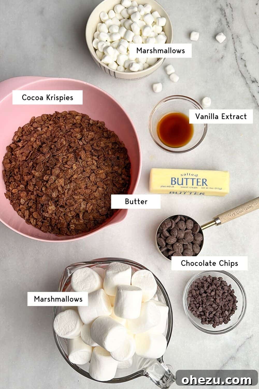 Cozy Cocoa Crisps 4 A collection of ingredients laid out, including cocoa rice cereal, mini marshmallows, chocolate chips, butter, and vanilla extract, ready for making Hot Cocoa Rice Krispie Treats.
