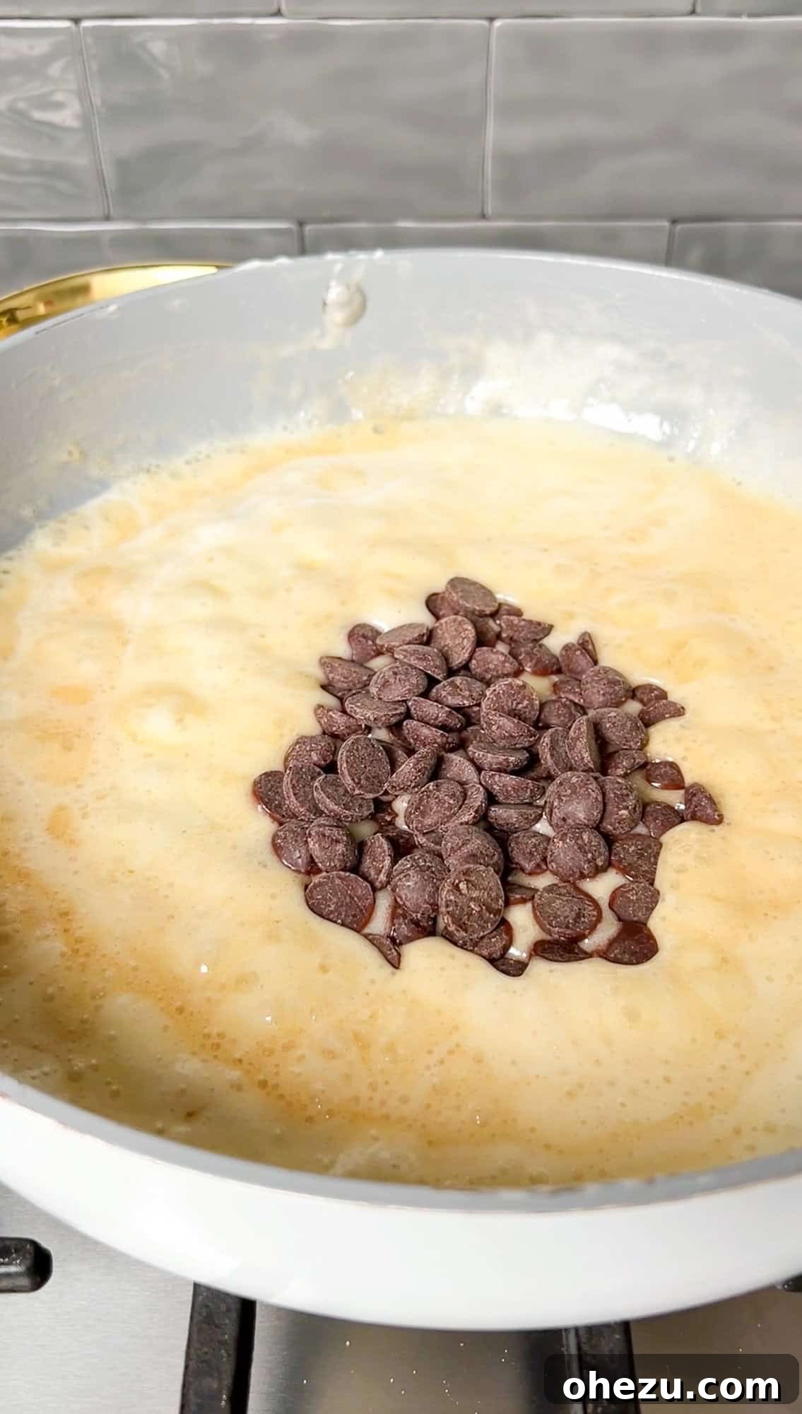 Cozy Cocoa Crisps 7 Chocolate chips being stirred into the warm, melted marshmallow and butter mixture in a nonstick pan.