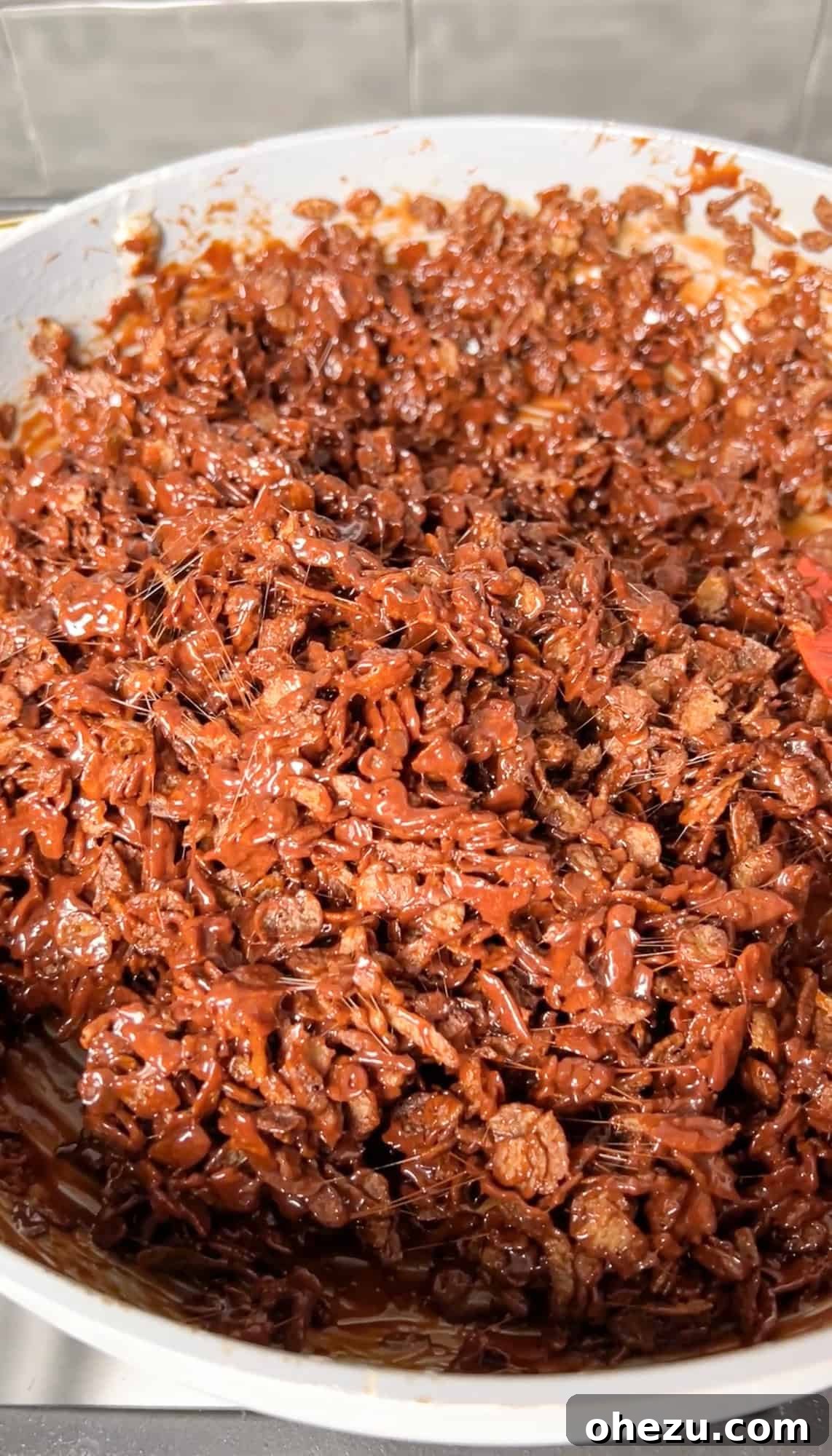 Cozy Cocoa Crisps 9 Cocoa Krispies cereal being folded into the rich, chocolatey marshmallow mixture, ensuring every piece is coated.