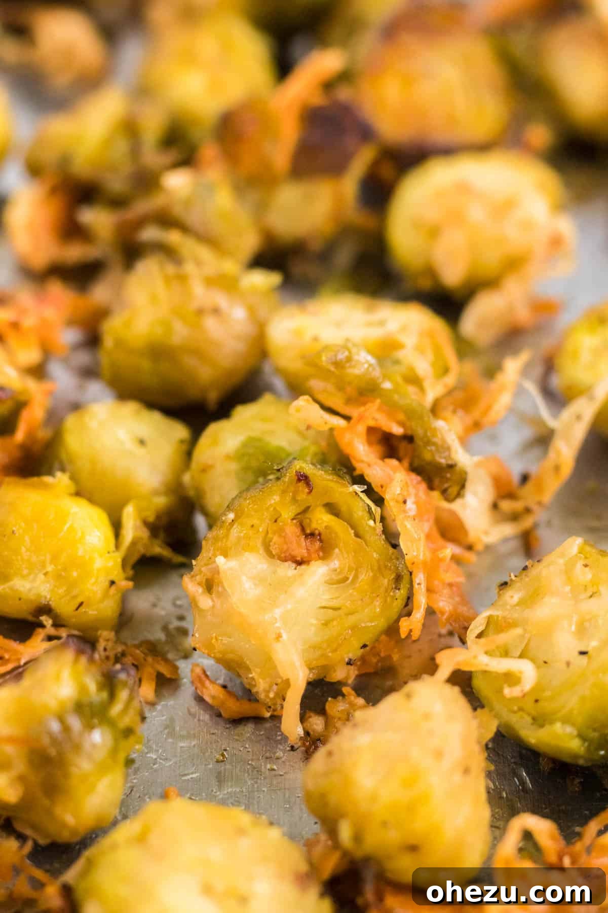 Close-up of a single roasted Brussels sprout with a golden, crispy Parmesan cheese crust, showcasing its perfect texture.
