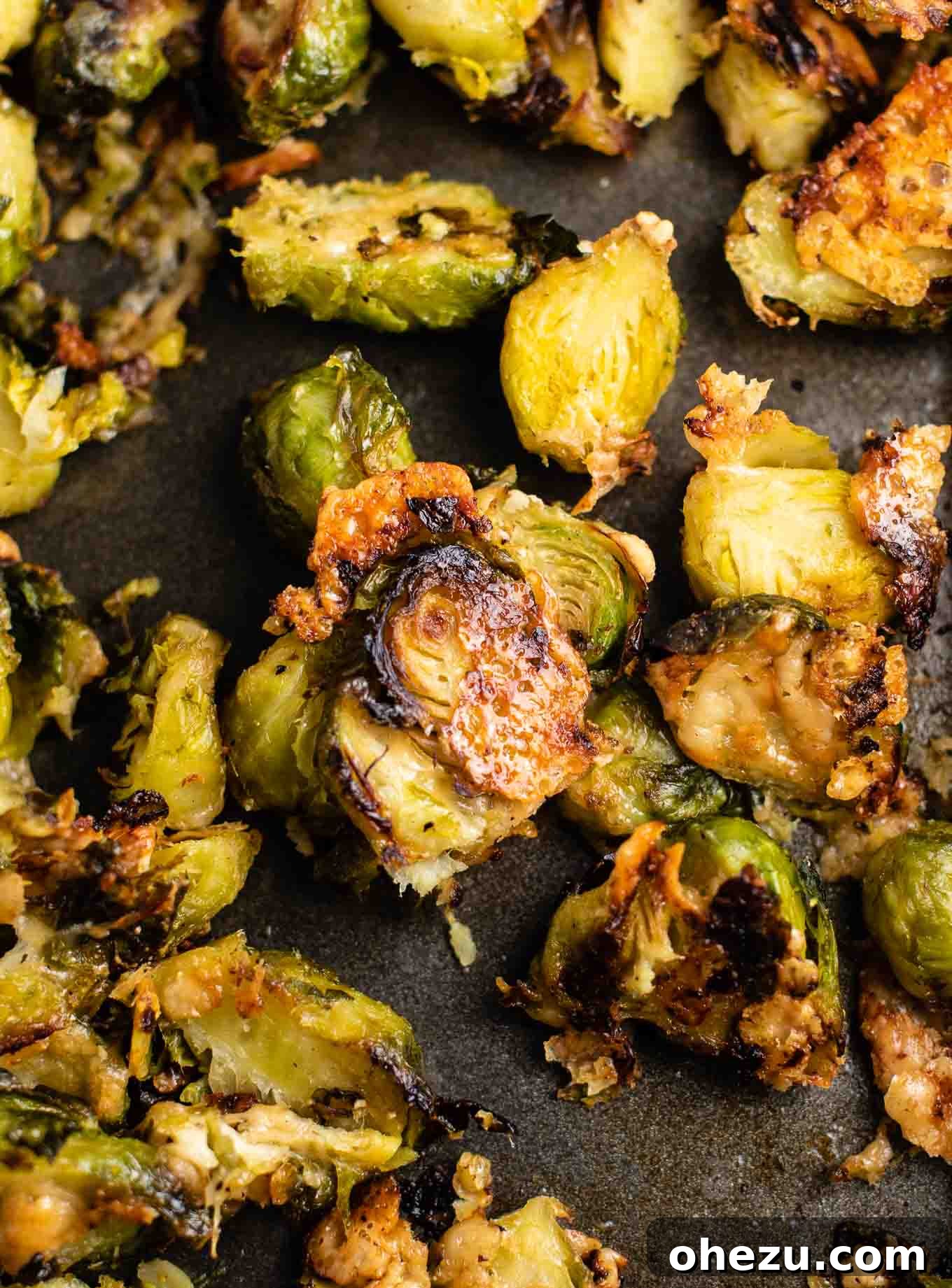 Close-up view of frozen Brussels sprouts spread in an even layer on a black non-stick baking sheet, ready for roasting in the oven.
