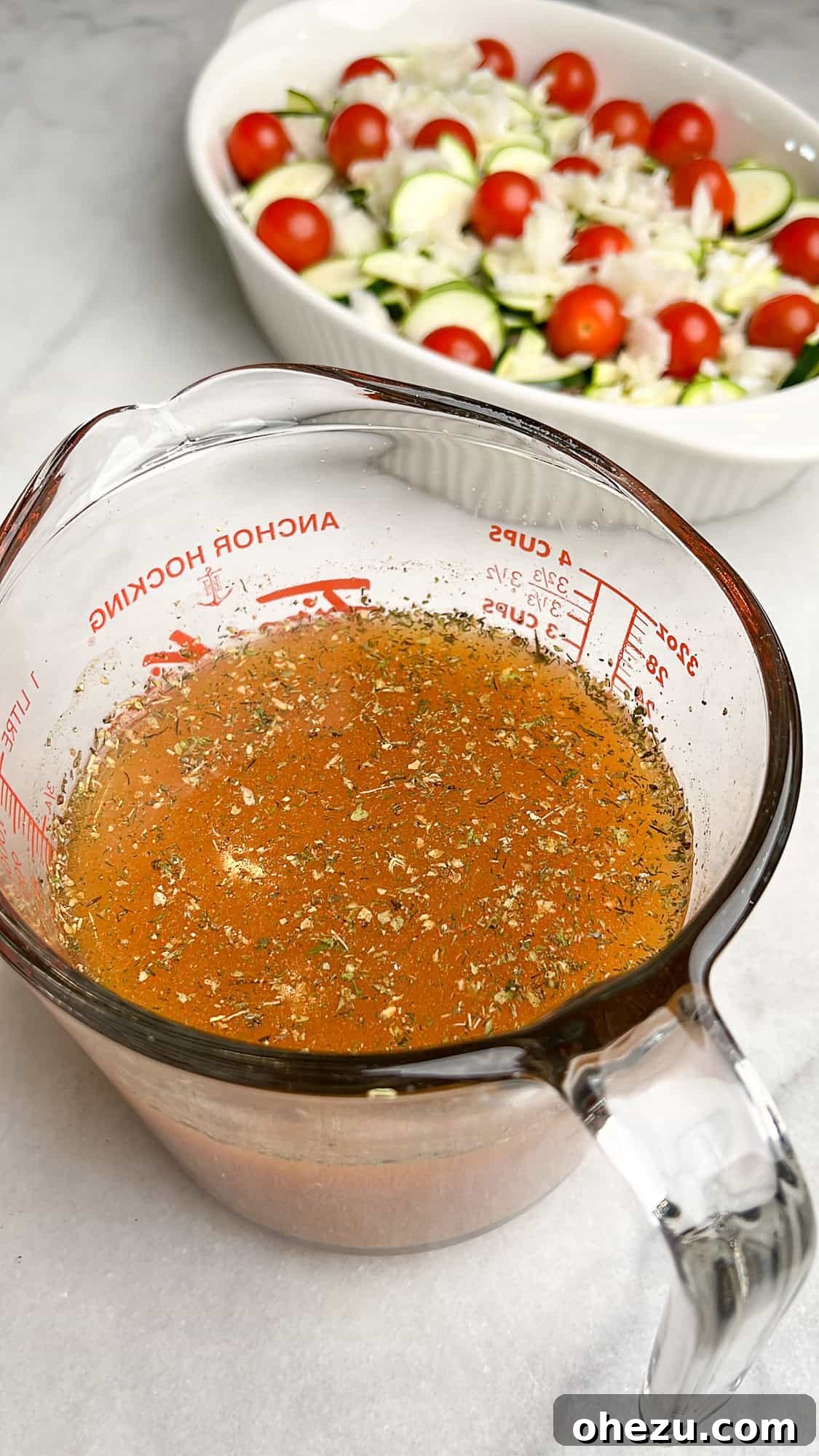 Zesty Greek Chicken Casserole 10 Chicken stock seasoned with paprika and Greek spices in a measuring cup, ready to be poured over the casserole.