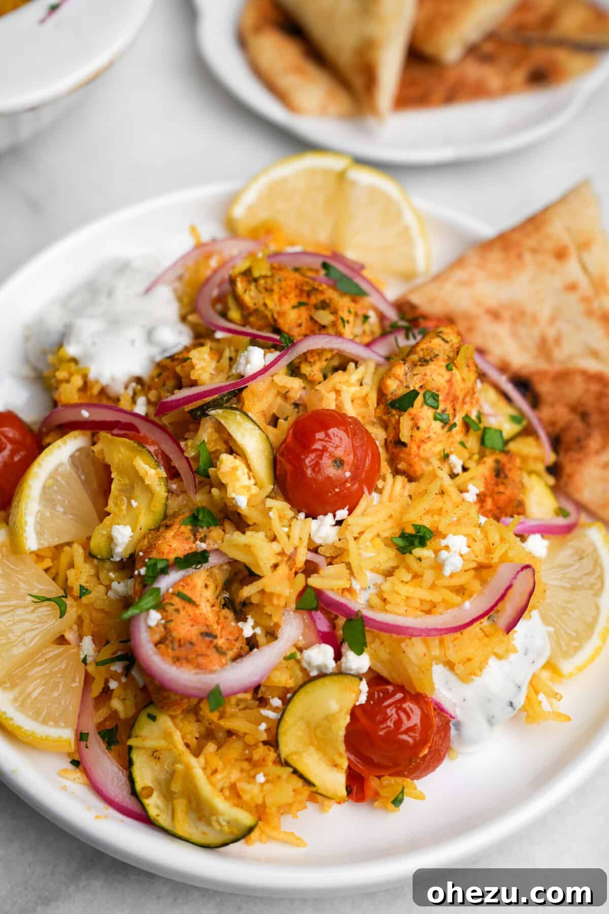 Zesty Greek Chicken Casserole 3 Portion of chicken tzatziki casserole served on a white plate, accompanied by warm pita bread, showcasing its vibrant ingredients.