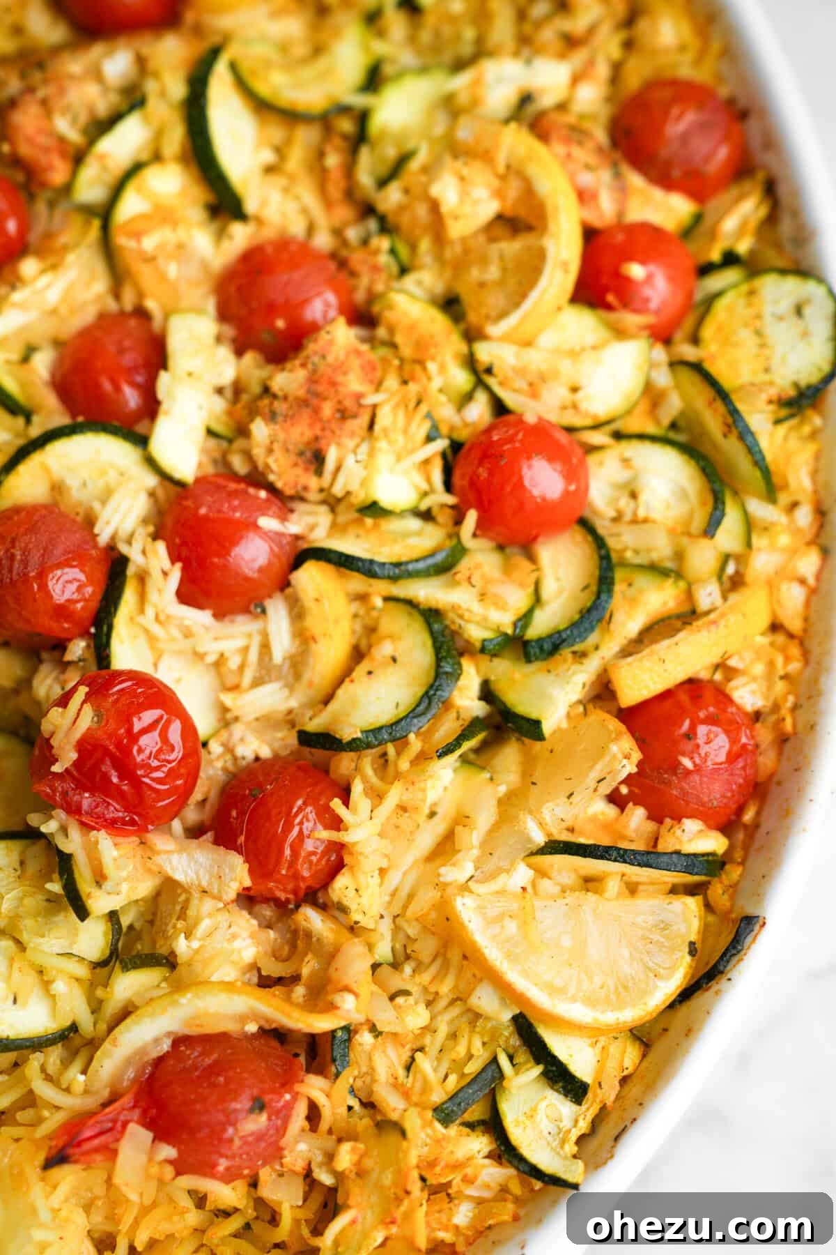 Zesty Greek Chicken Casserole 5 Chicken tzatziki casserole baking in a dish, before the final toppings are added, showing cooked chicken, rice, and vegetables.