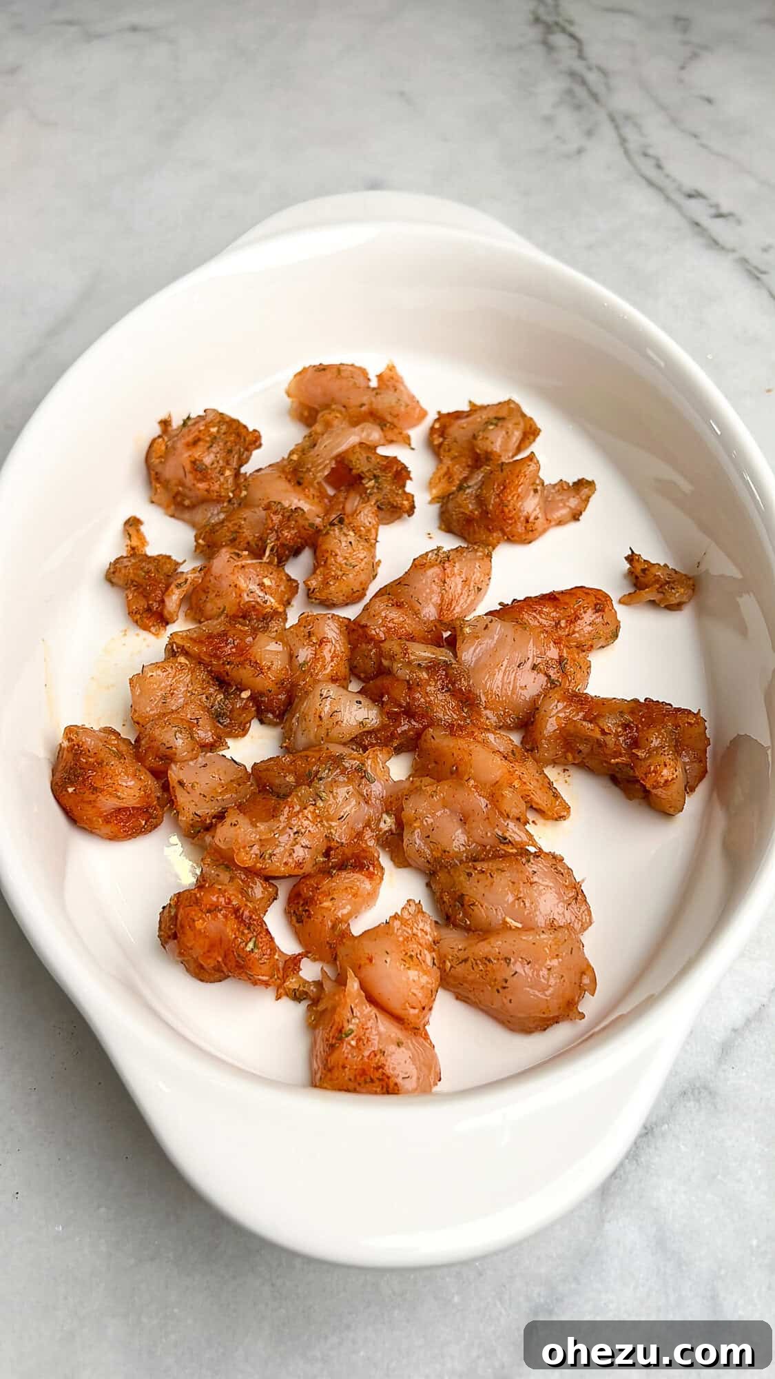 Zesty Greek Chicken Casserole 7 Diced chicken breast seasoned and spread in a casserole dish.