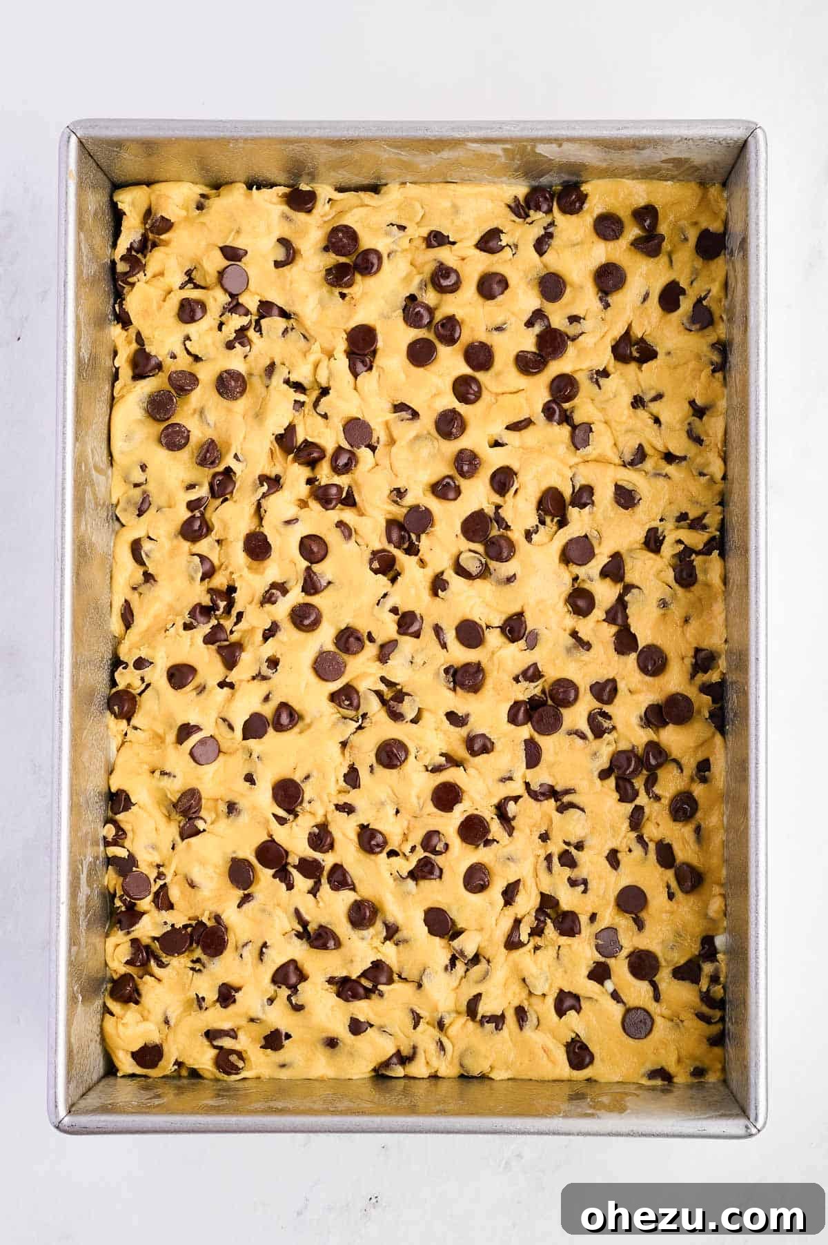 Cake mix cookie bar batter smoothly pressed into a 9x13 inch baking dish