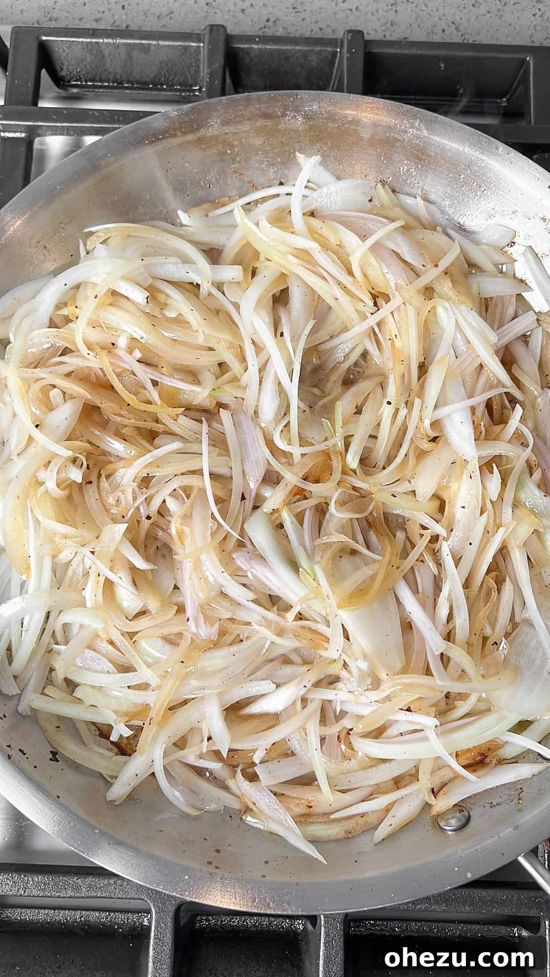 Sliced onions cooking in the pan, starting to soften