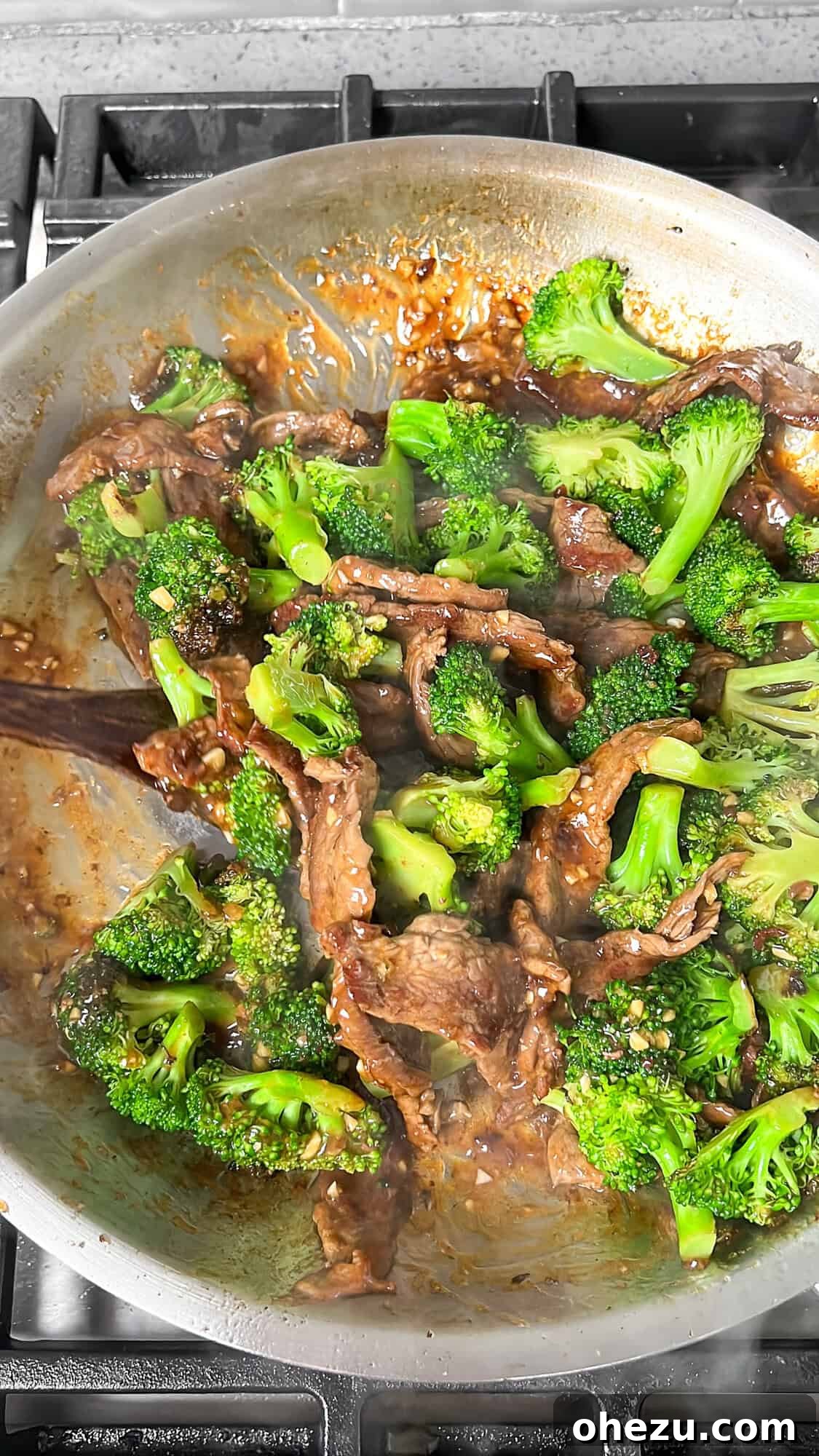 Beef and broccoli finishing up in the pan, coated in sauce
