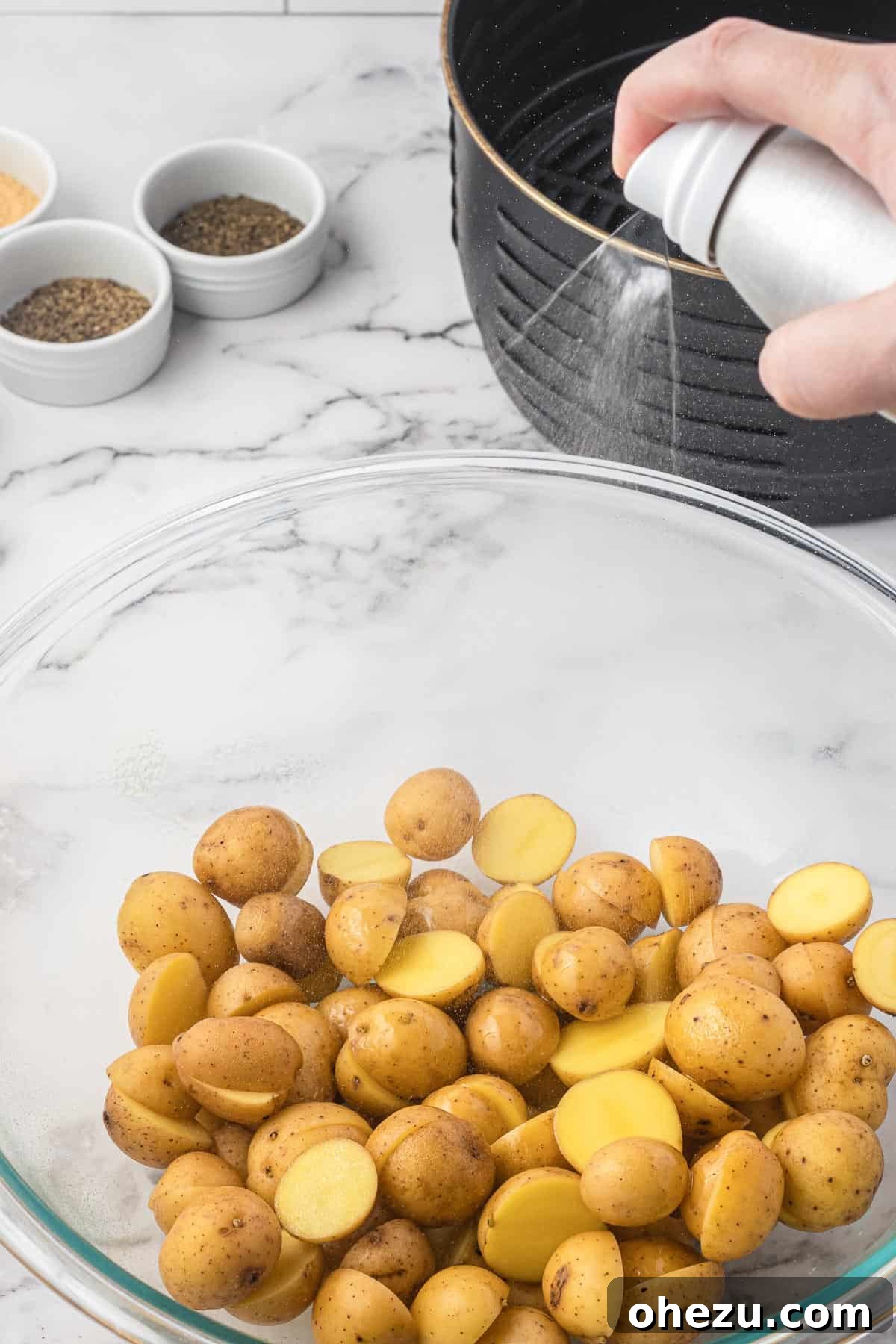 Crispy Air Fryer Baby Potatoes 6 spraying a bowl of potatoes with olive oil spray
