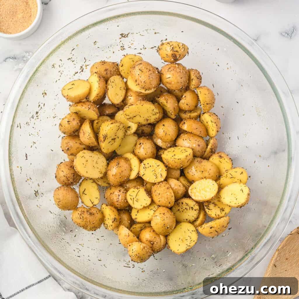 Crispy Air Fryer Baby Potatoes 8 baby potatoes in a bowl mixed together with olive oil and spices