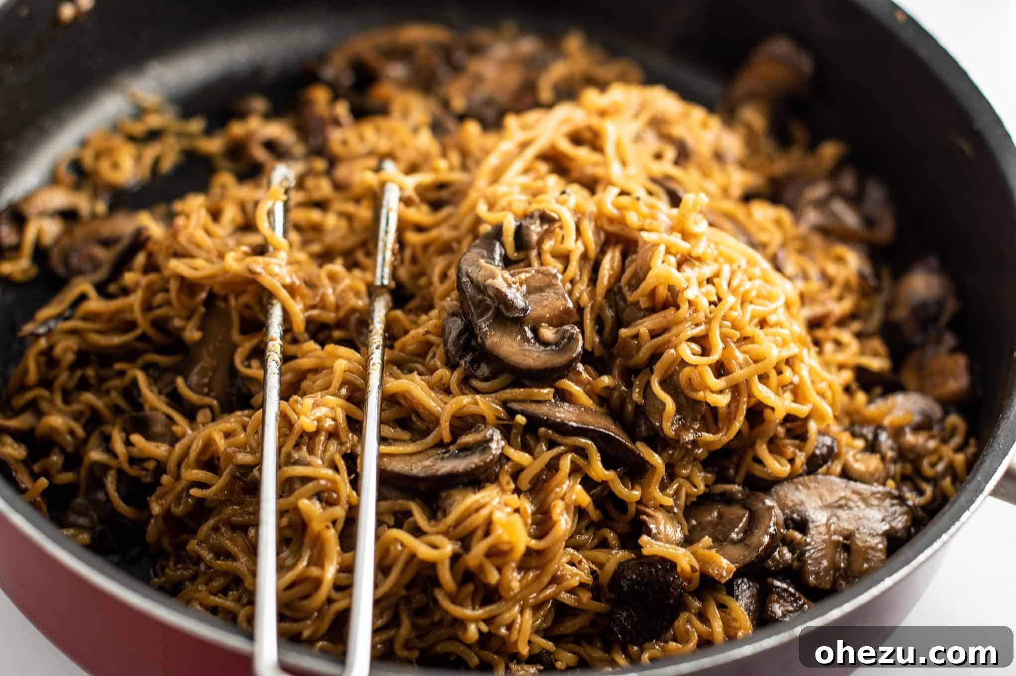 ramen noodles with mushrooms in a vibrant red jumbo cooker pan, hot and steamy