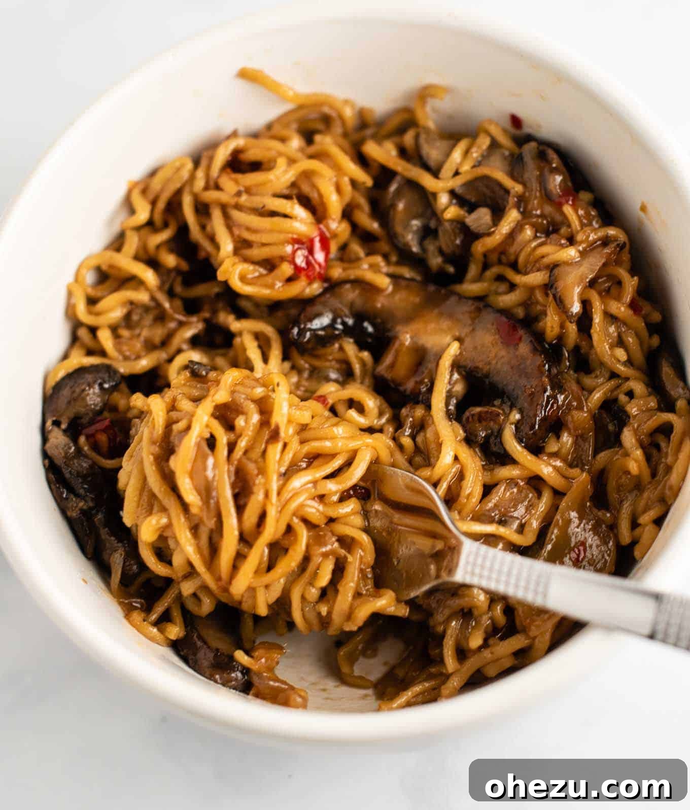 stir fry noodles with mushrooms and sweet chili sauce in a white bowl, garnished beautifully