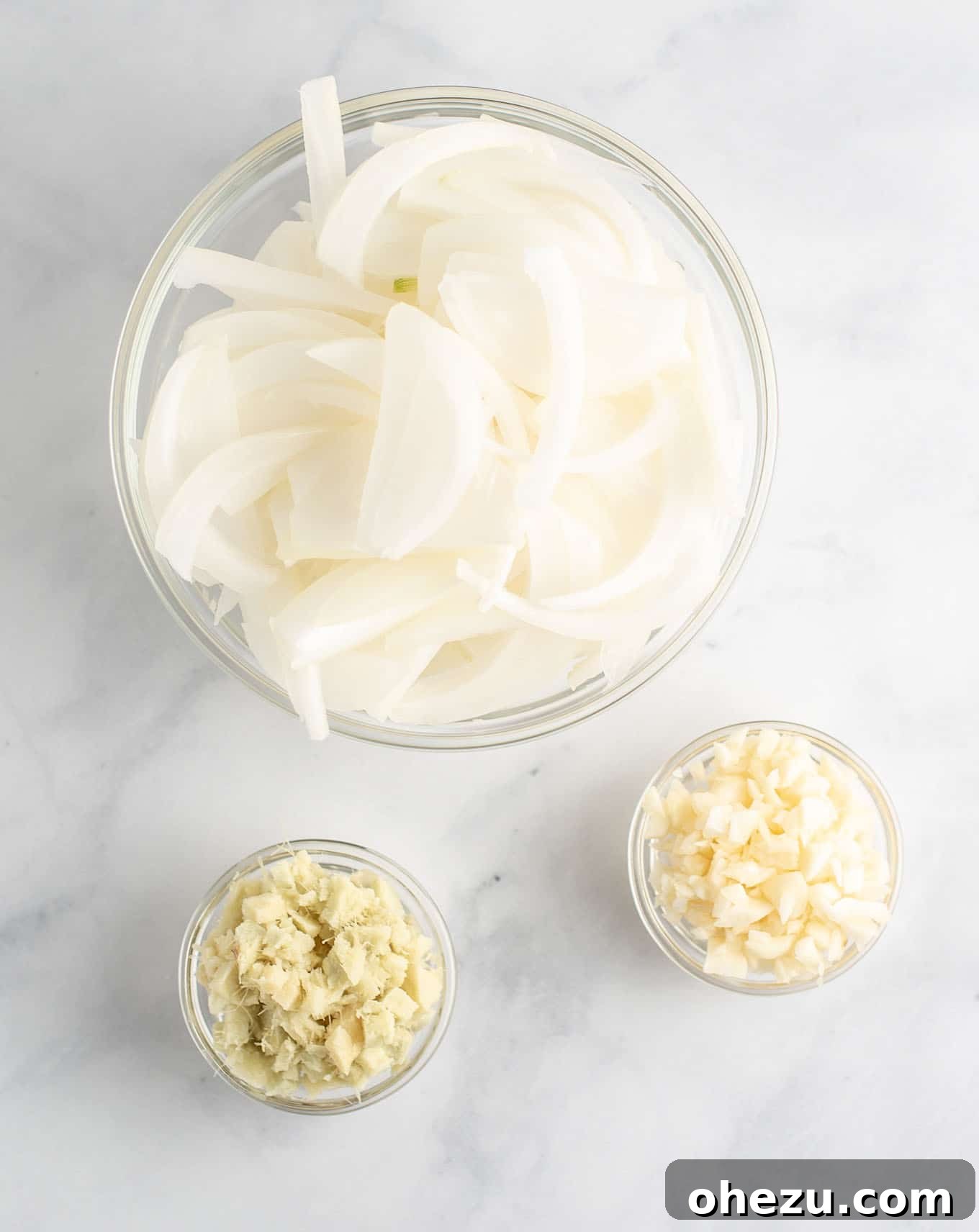 minced garlic, sliced onion, and minced ginger in small bowls, ready for cooking
