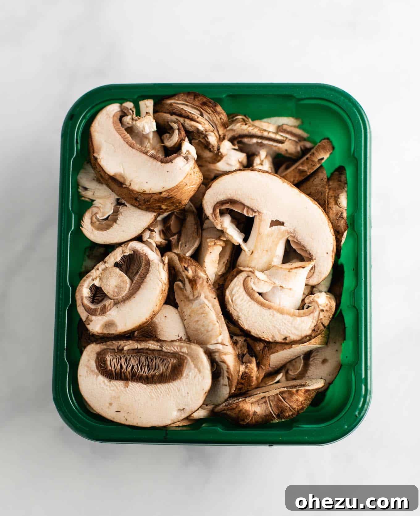 sliced baby bella mushrooms in a container, ready for cooking