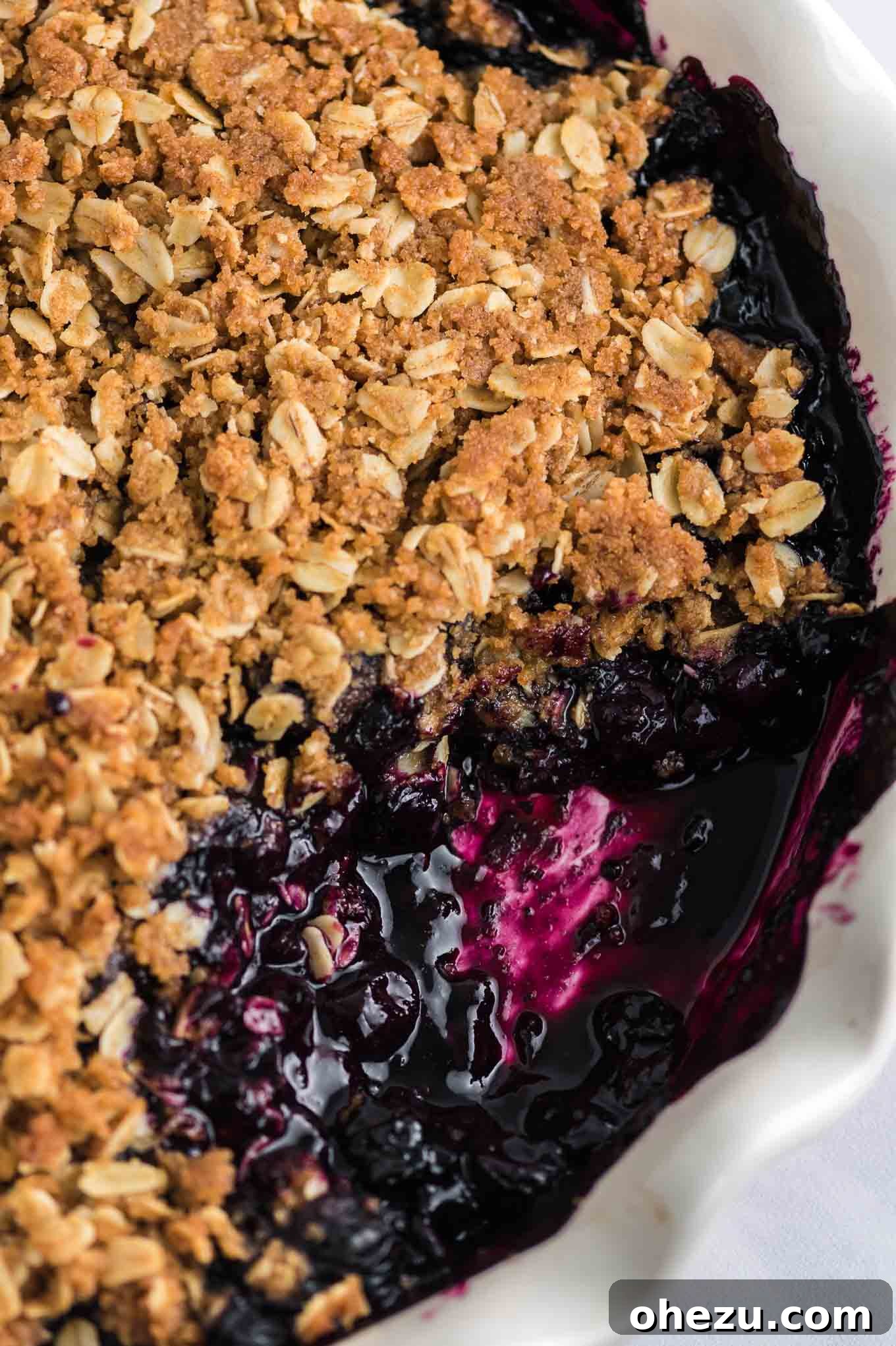 Blueberry crisp dish with a spoonful taken out, showcasing the rich filling and topping