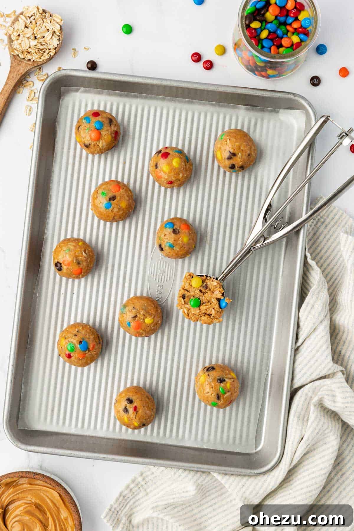 Ultimate Monster Cookie Fuel Bites 8 Rows of freshly rolled monster cookie bites arranged neatly on a baking sheet lined with wax paper.