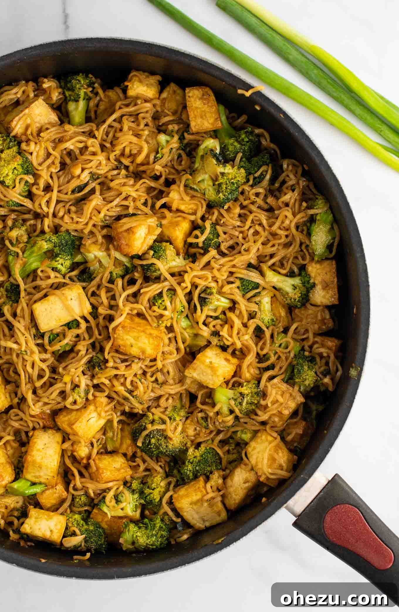 Overhead view of a skillet filled with broccoli tofu ramen noodles, freshly cooked and coated in sauce