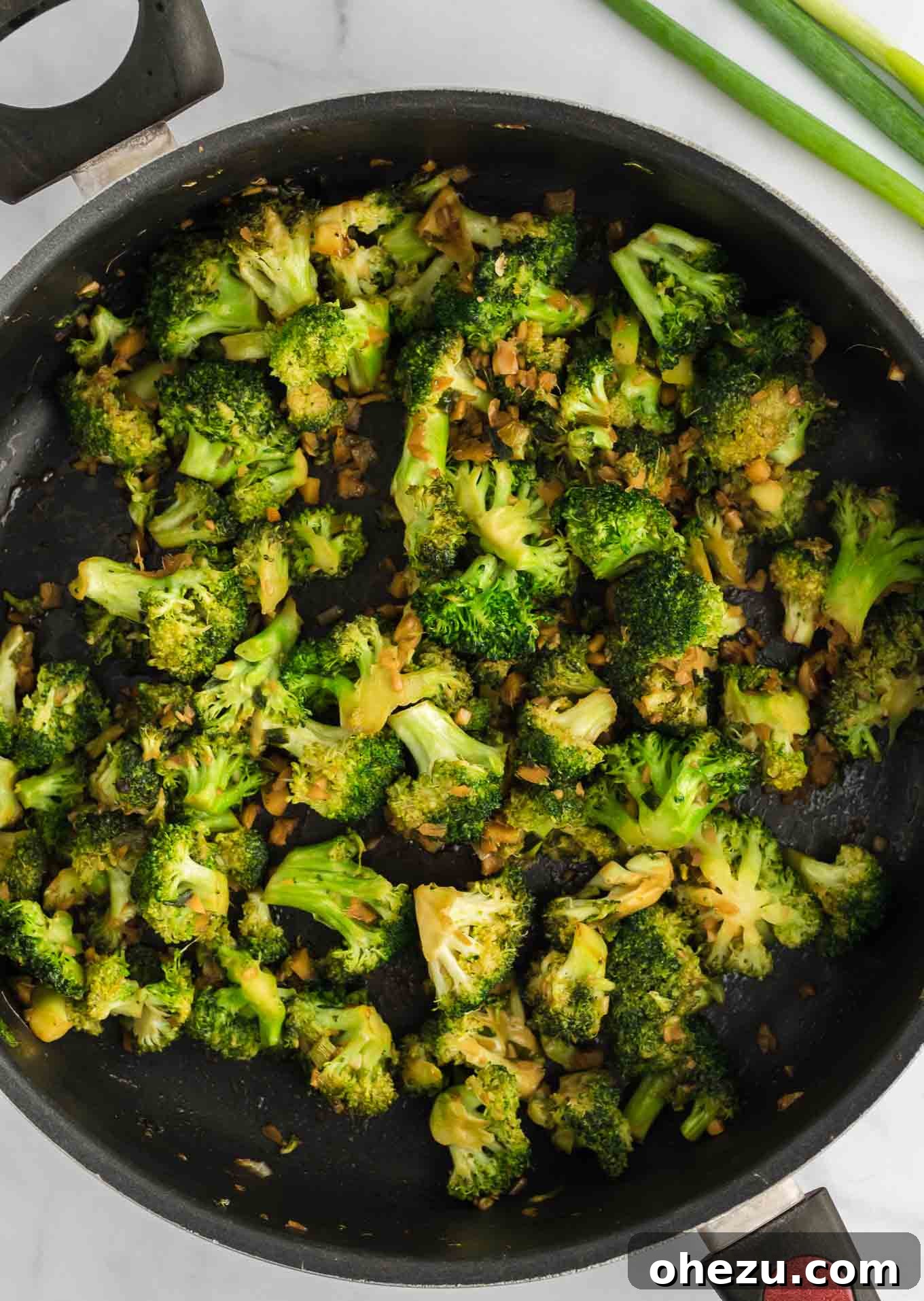 Freshly cooked broccoli florets in a large skillet, glistening with a light coating of sauce