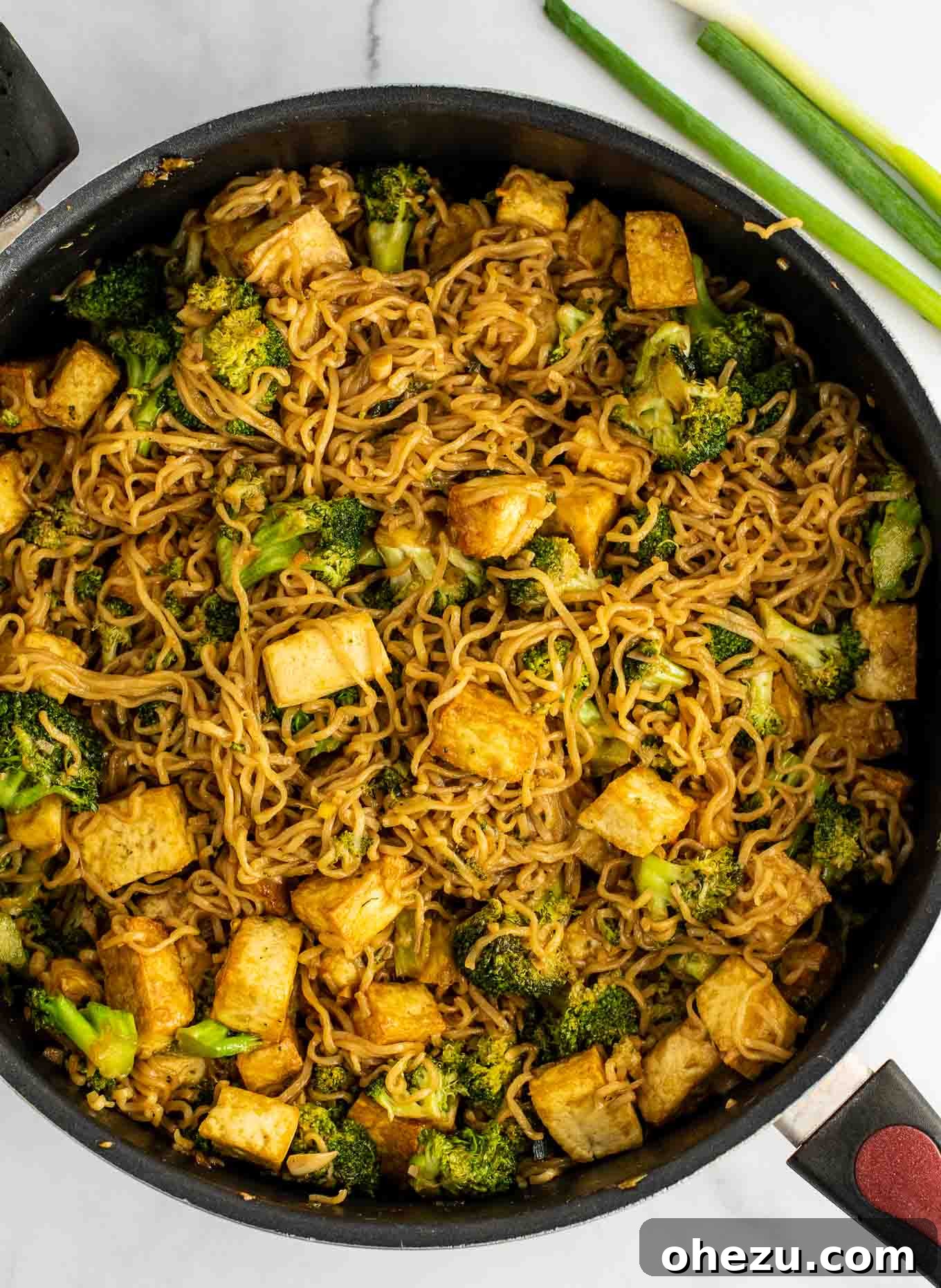 Cooked ramen noodles mixed with crispy tofu and broccoli in a skillet, coated in a delicious stir fry sauce